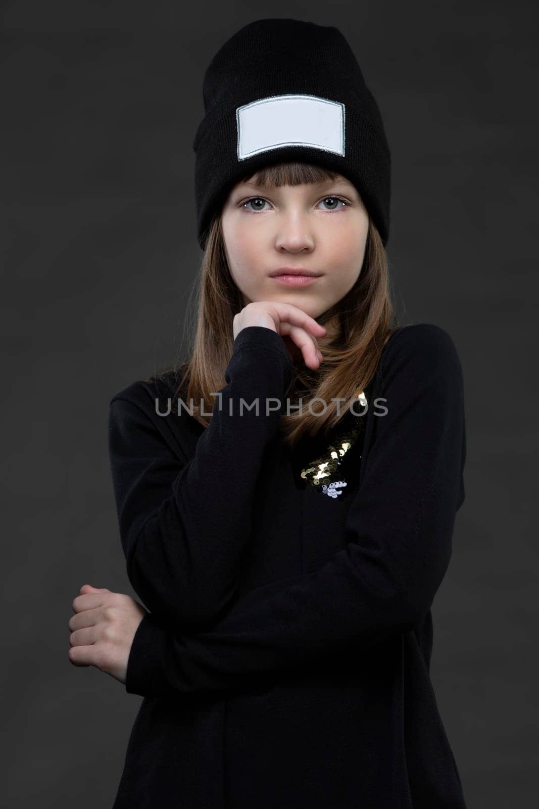 Portrait of a beautiful teenage girl in dark clothes on gray.