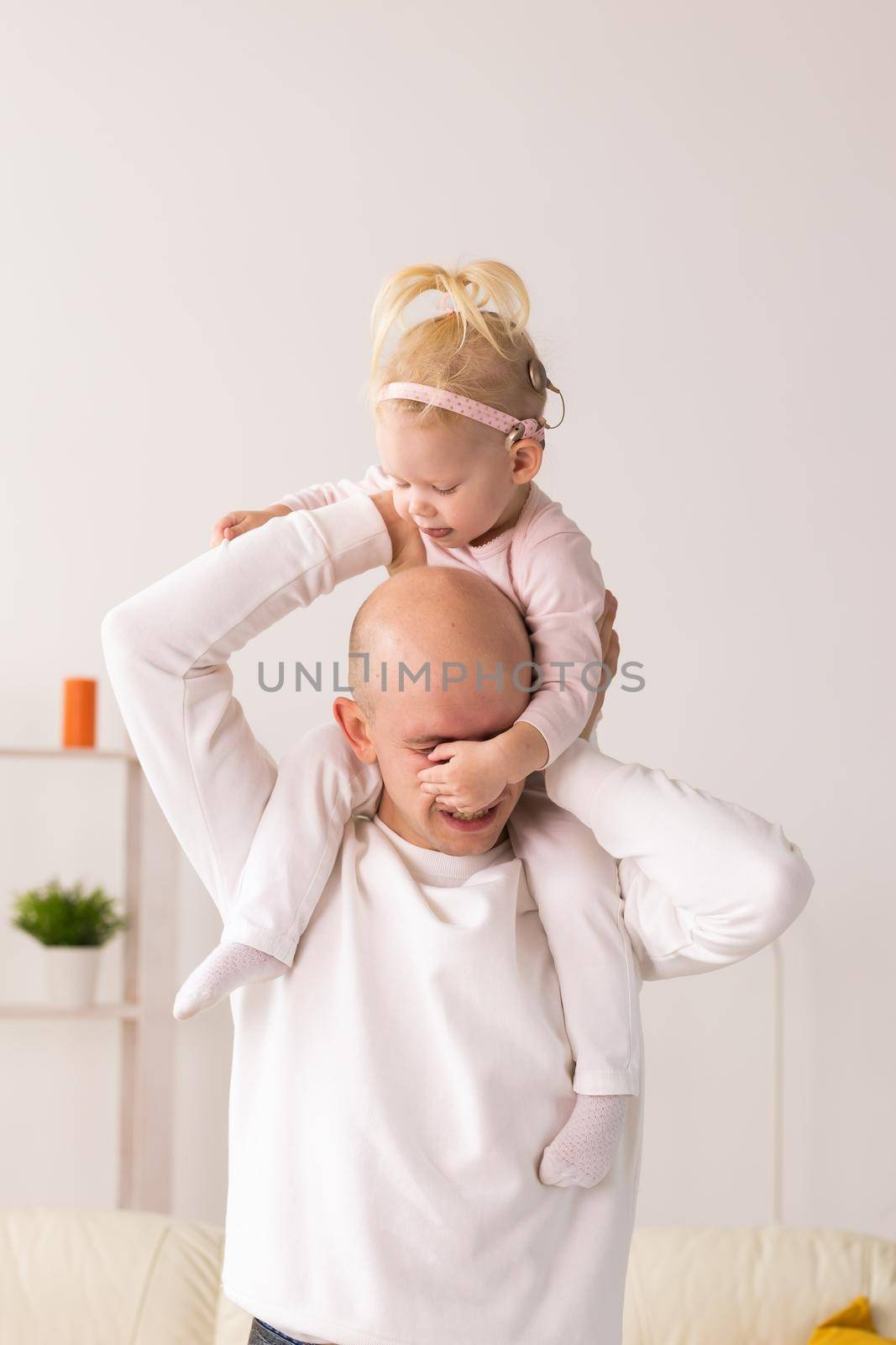 Baby with cochlear implants playing with her mother and father at home.