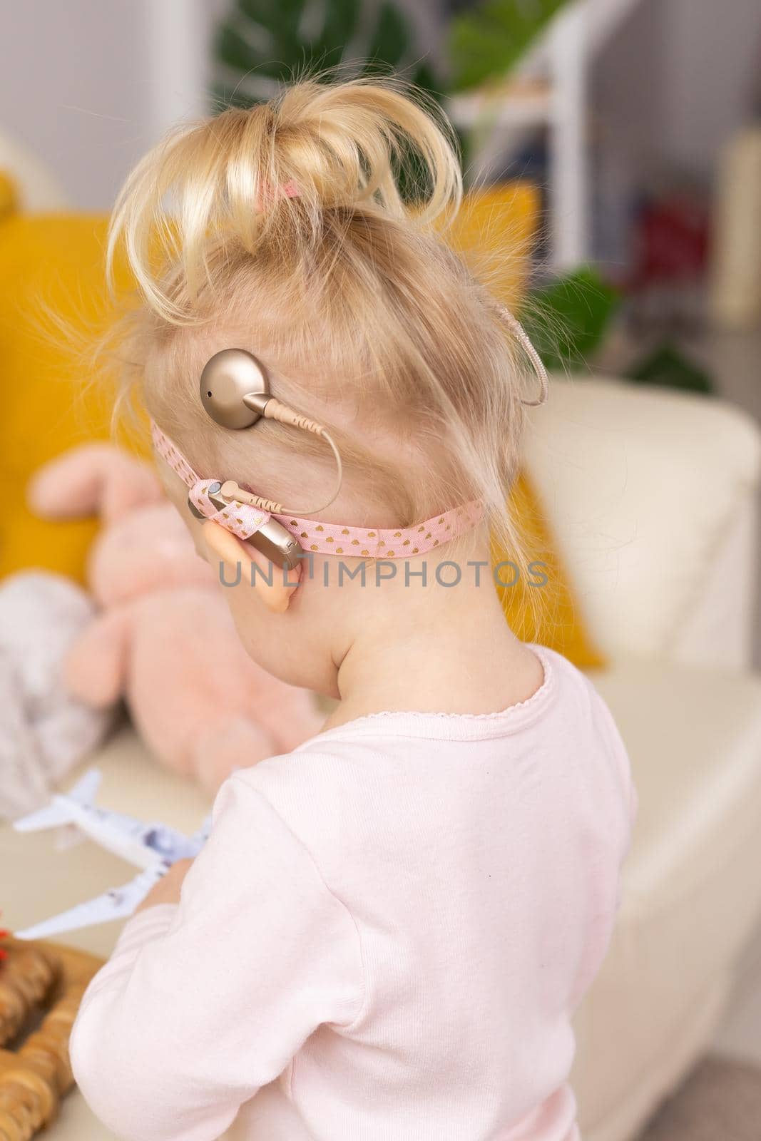 Baby with cochlear implants having fun at home. Deafness and medical technology