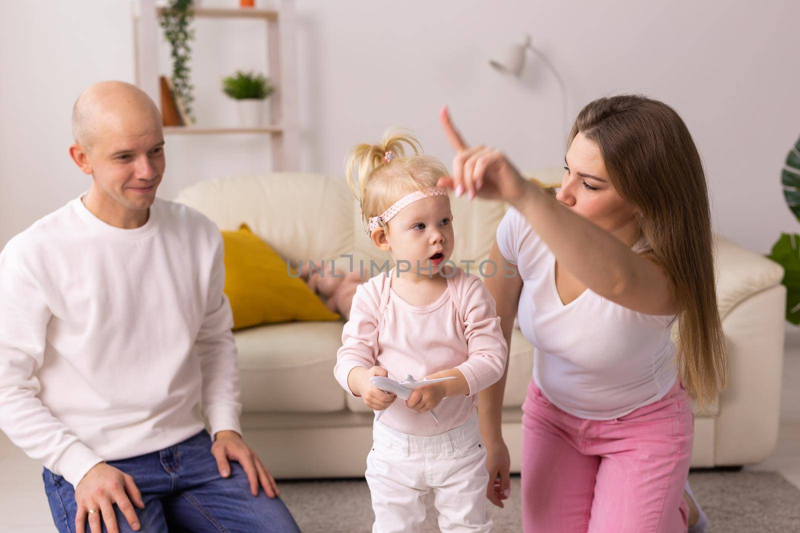 Baby child with hearing aids and cochlear implants plays with parents on floor. Deaf and rehabilitation concept by Satura86