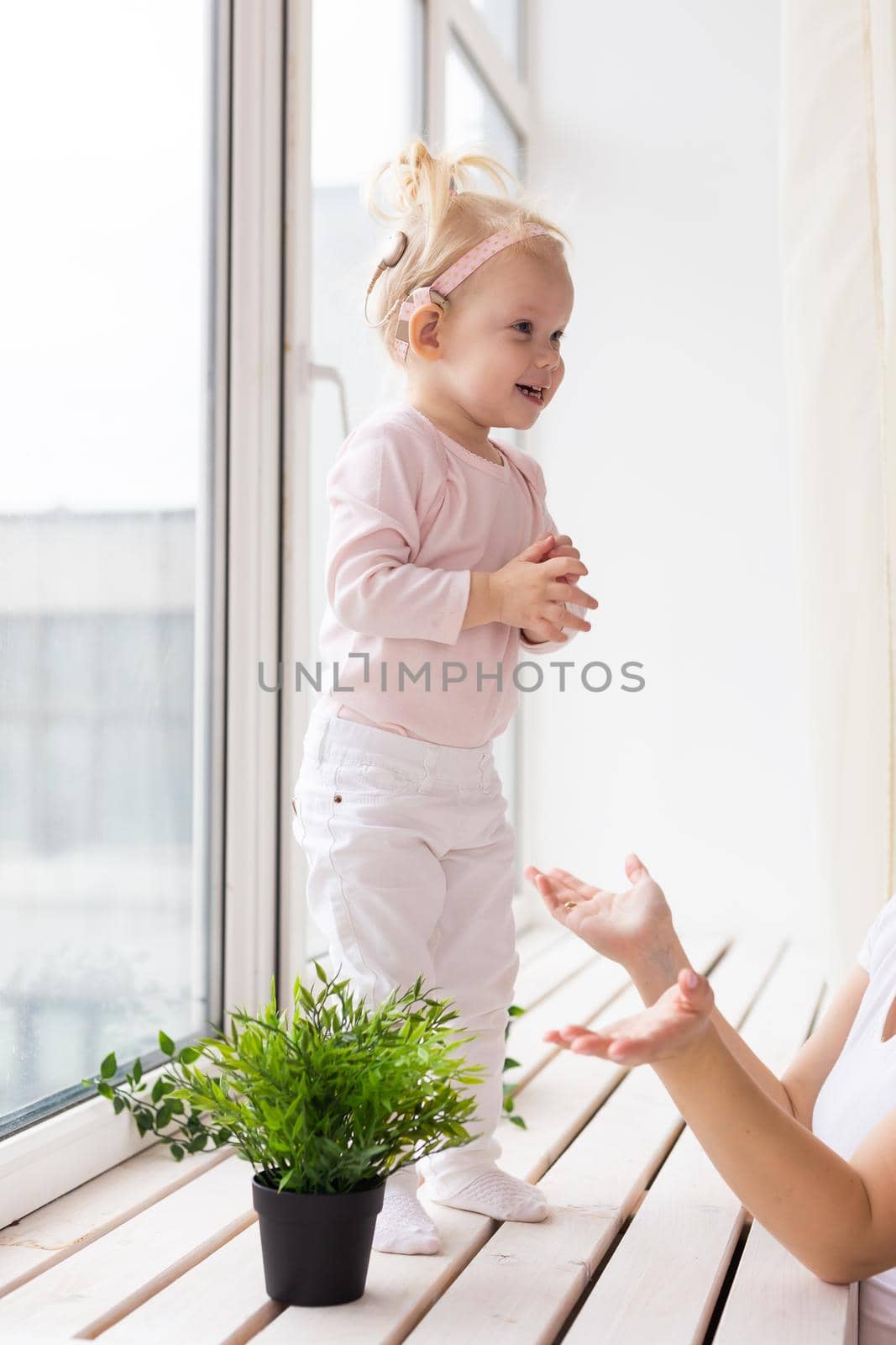 Baby with cochlear implants having fun at home. Deafness and medical technology