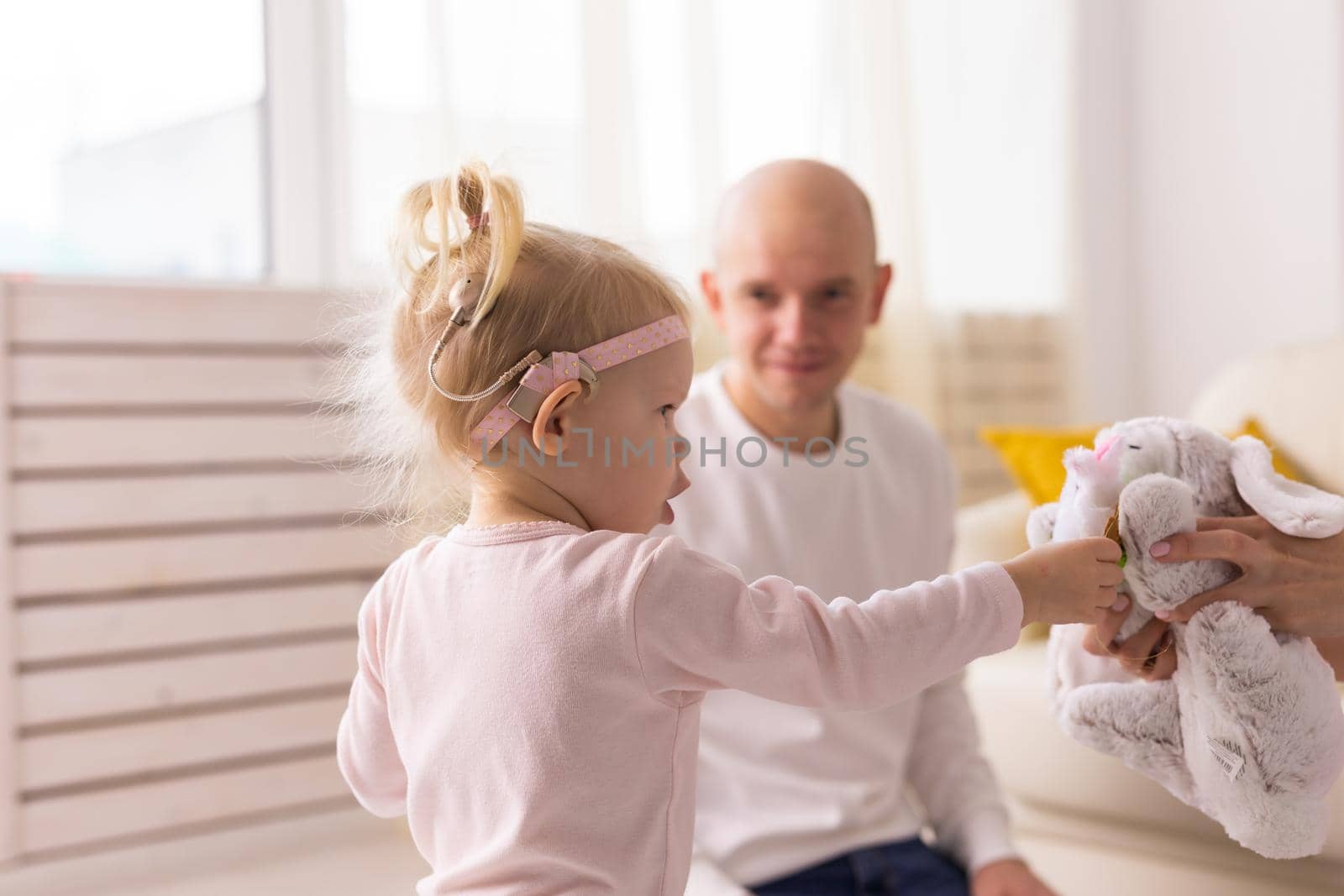 Baby with cochlear implants playing with her father at home. Deafness and medical technology concept by Satura86