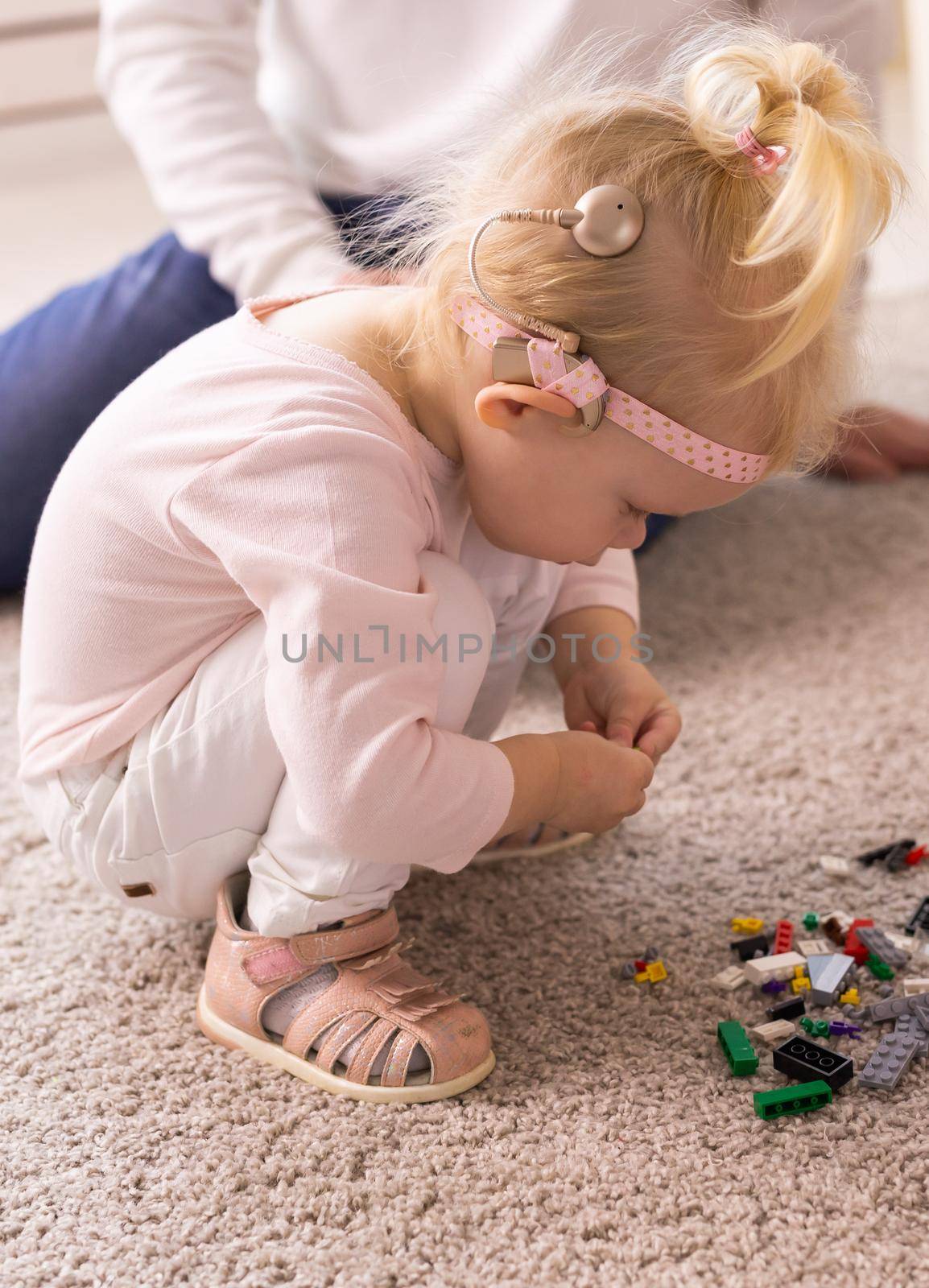 Baby with cochlear implants having fun at home. Deafness and medical technology