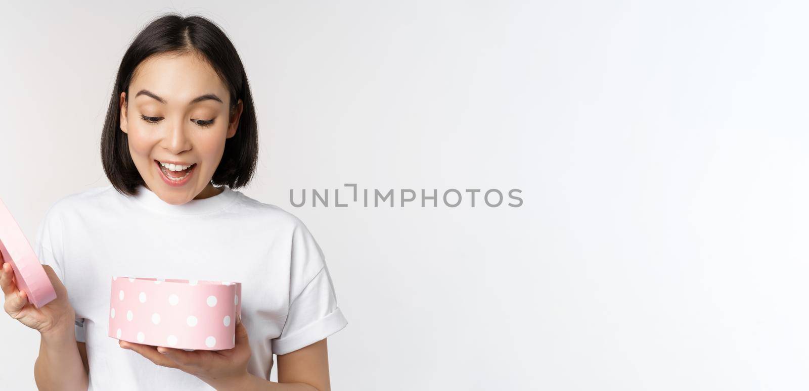 Happy asian woman, girlfriend open box with valentines day gift, receive romantic present, standing over white background. copy space