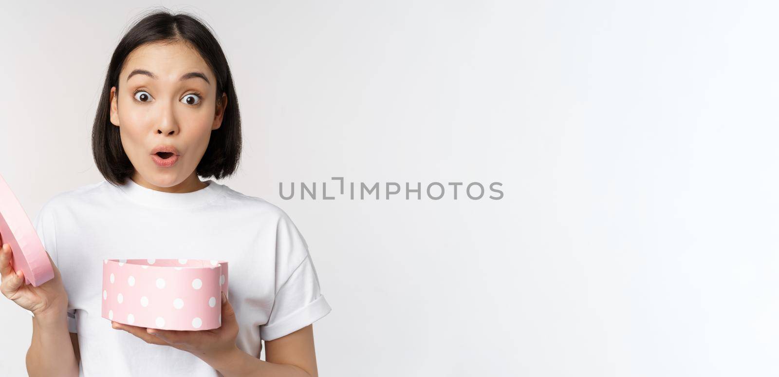 Happy asian woman, girlfriend open box with valentines day gift, receive romantic present, standing over white background by Benzoix