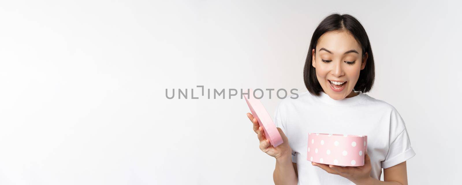 Happy asian woman, girlfriend open box with valentines day gift, receive romantic present, standing over white background by Benzoix
