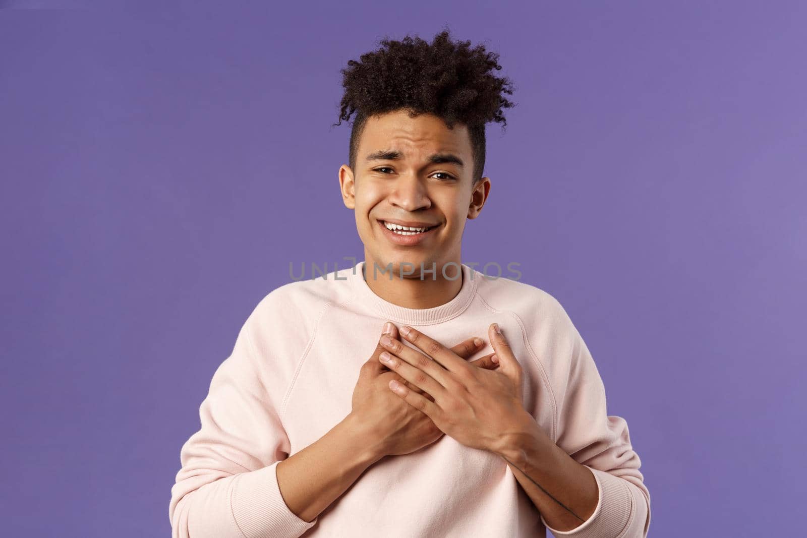 Close-up portrait of handsome silly hispanic guy with dreads, place hands on heart and sighing as contemplate something adorable speaking from all his soul, thanking for praises, purple background.