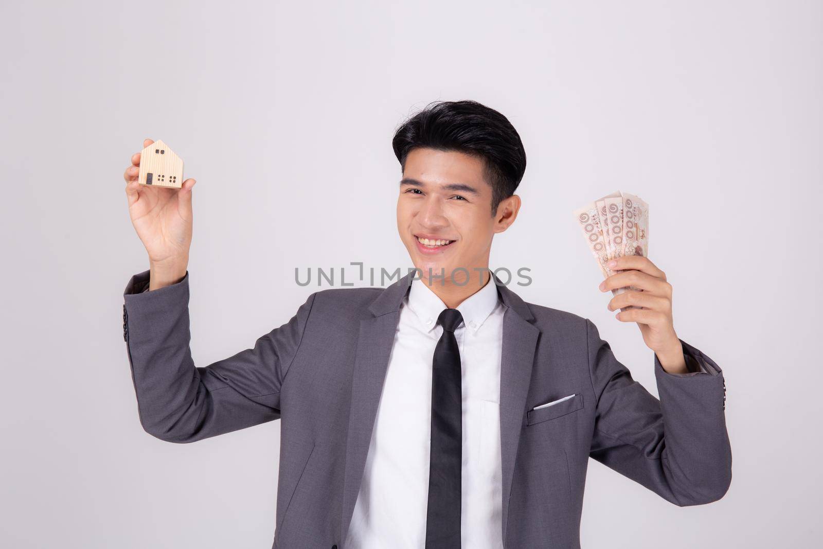 Young asian business man holding home and money Thai for planning saving future, insurance agent and credit, debt and loan of finance, purchase home and refinance, investment about real property. by nnudoo