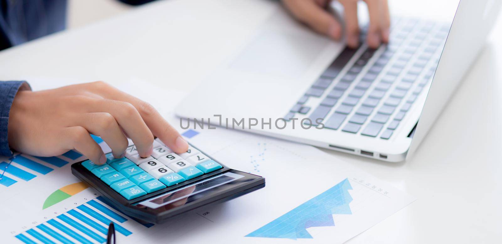 Hand of young asian business man working using calculator for planning accountant, graph for finance and report statistics, investment and profit of income, businessman analyzing with chart.