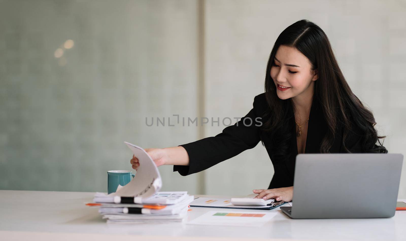 Charming asian business accountant woman working with computer and calculator for business and financial expense.