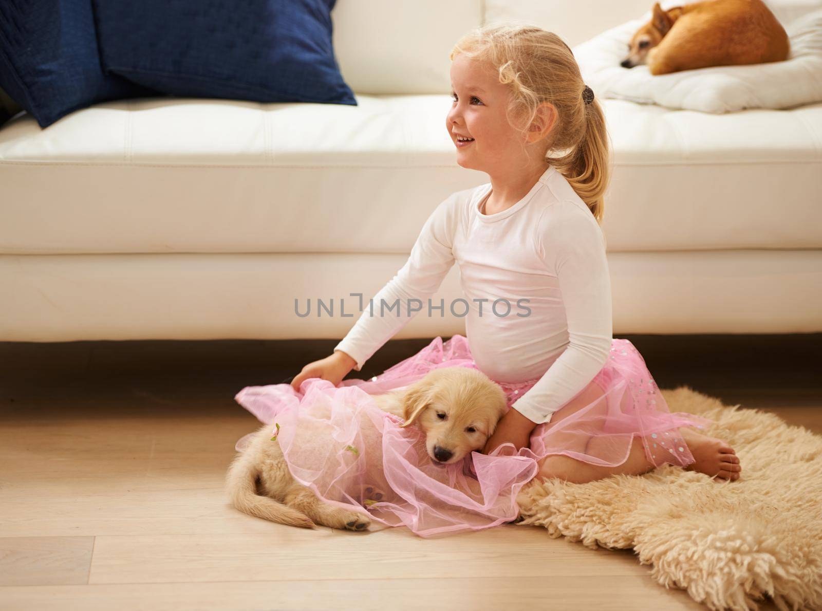Shot of a little girl in a tutu playing with a puppy.