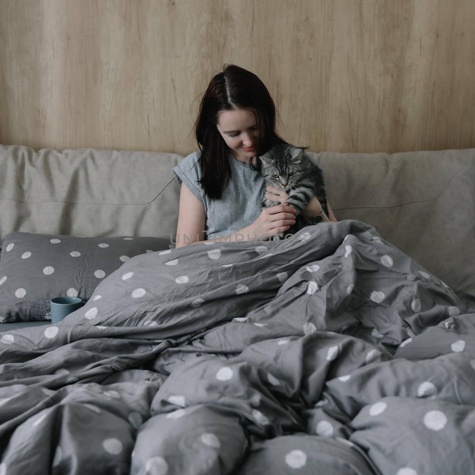 morning, coziness, cozy home concept - a young woman with her cat in bed at home.