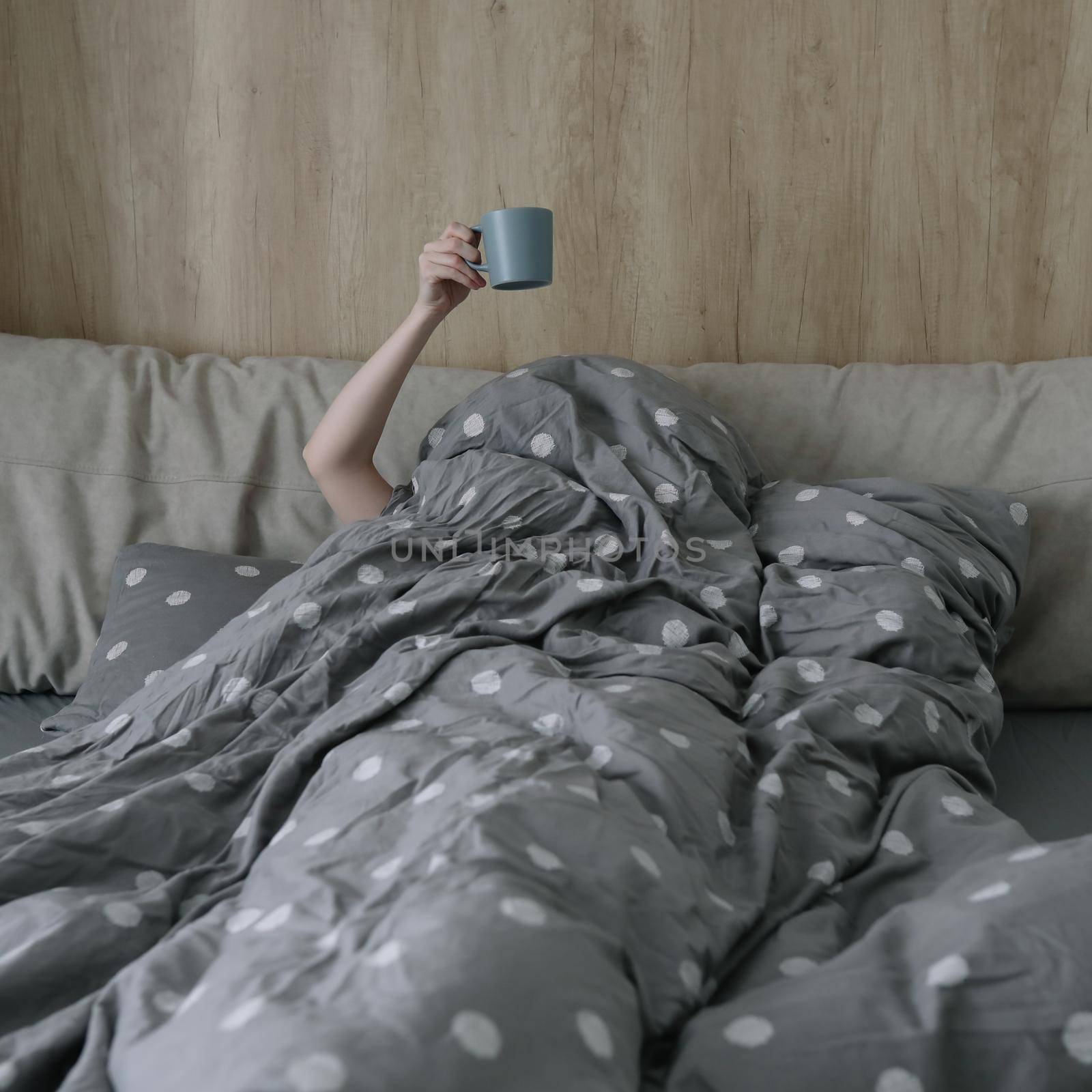 morning, coziness, cozy home concept - a hand with cup of coffee or tea in bed at home.