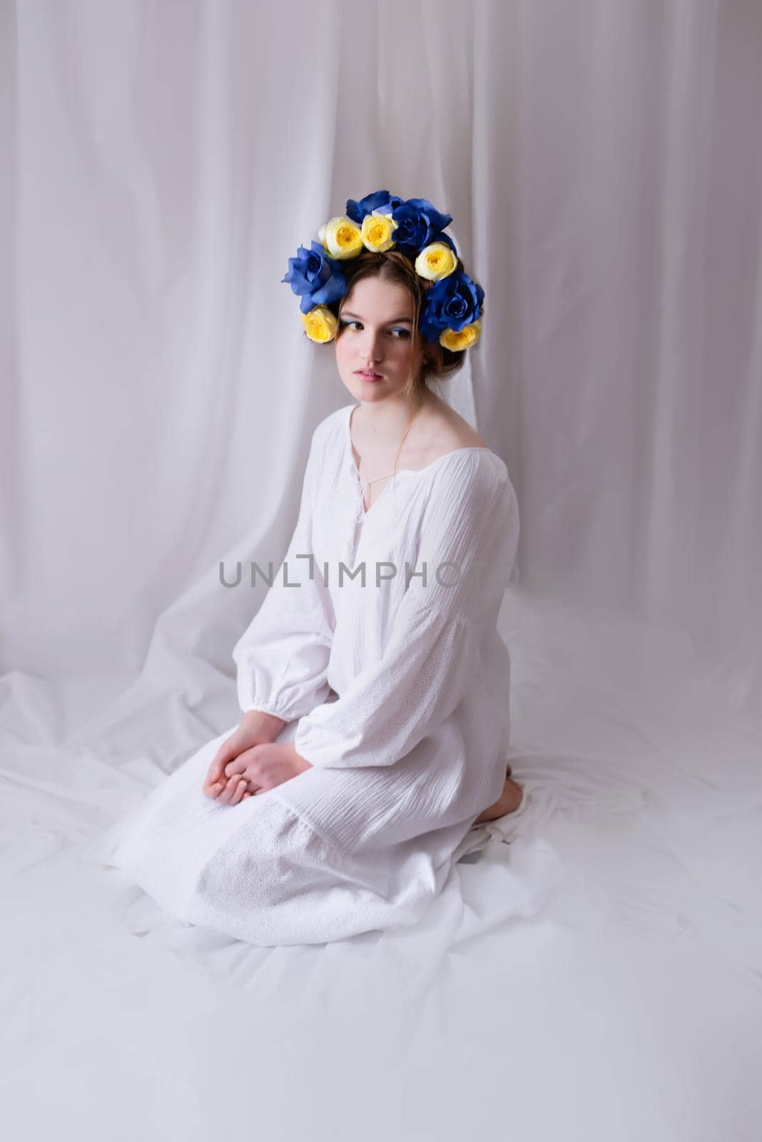 Beautiful Ukrainian woman in a white dress and floral wreath on white background . Symbol of the Ukrainian yellow blue flag. The calm lady. Peace in Ukraine