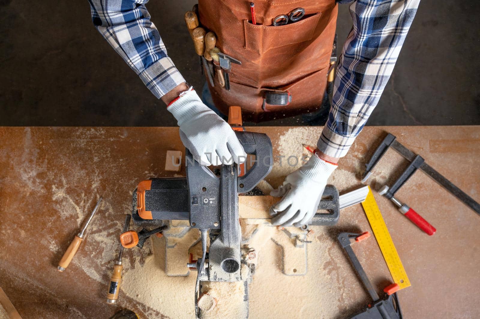 Top view of carpenter holding plank near circular saw in carpentry shop by HERRAEZ