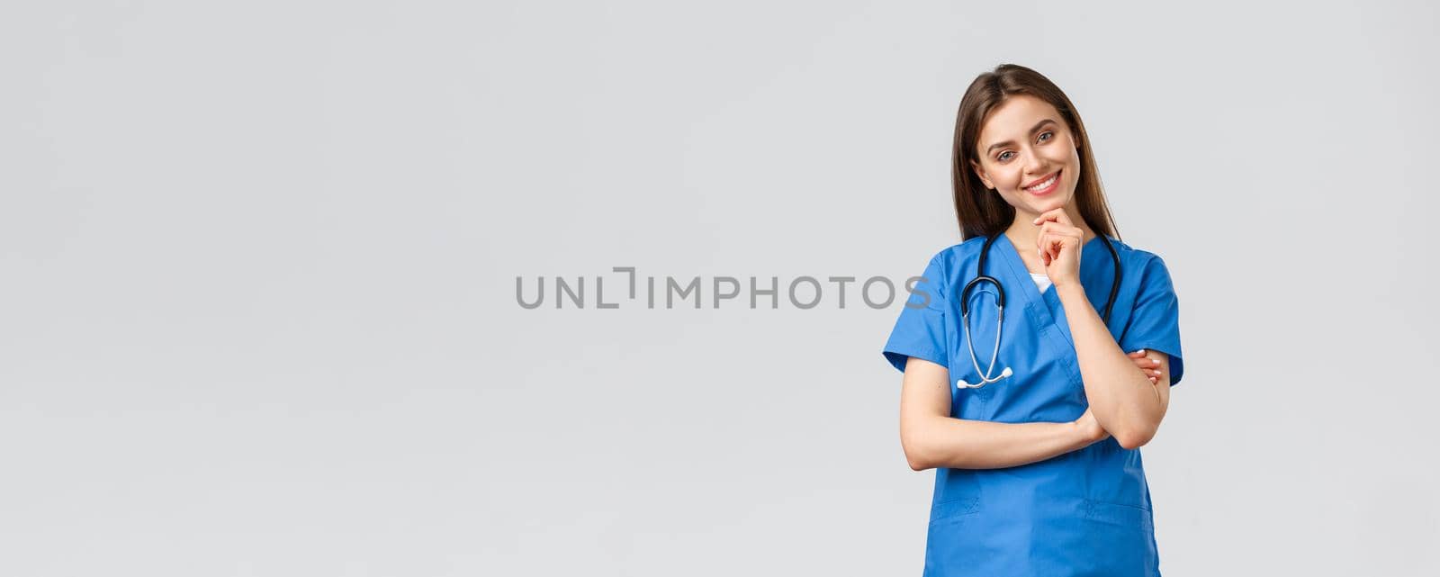 Medical workers, healthcare, covid-19 and vaccination concept. Upbeat smiling pretty nurse, doctor in blue scrubs, working clinic, looking with enthusiastic gaze camera, listening to coworker.