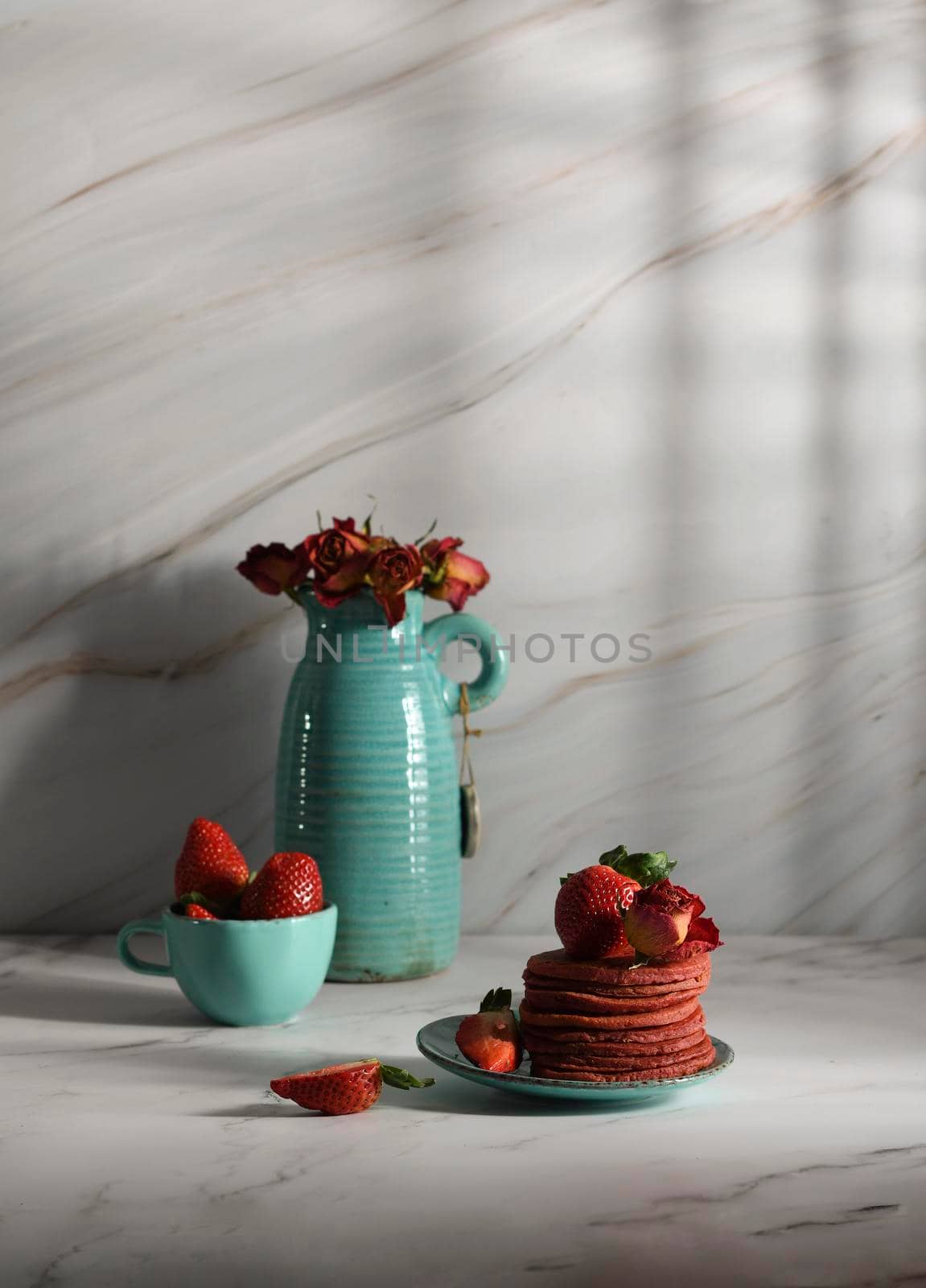 still life with pink strawberry pancakes on a turquoise plate with sour cream and fresh strawberries, cultural exotic food, creative breakfast for Valentine's holiday against a turquoise vase