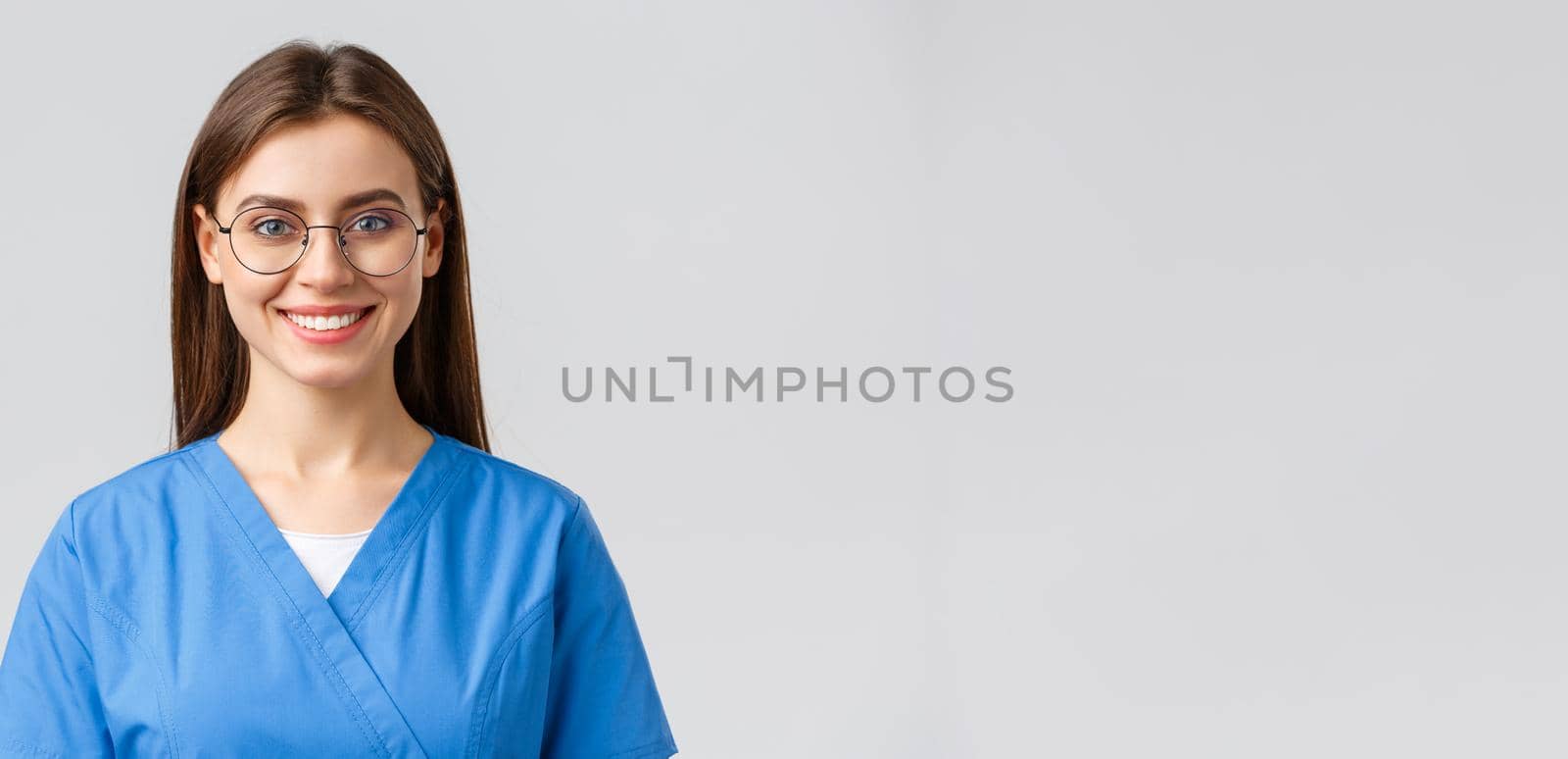 Healthcare workers, medicine, insurance and covid-19 pandemic concept. Cheerful optimistic female nurse, doctor or intern in clinic wearing scrubs and glasses, stay positive, smiling upbeat by Benzoix