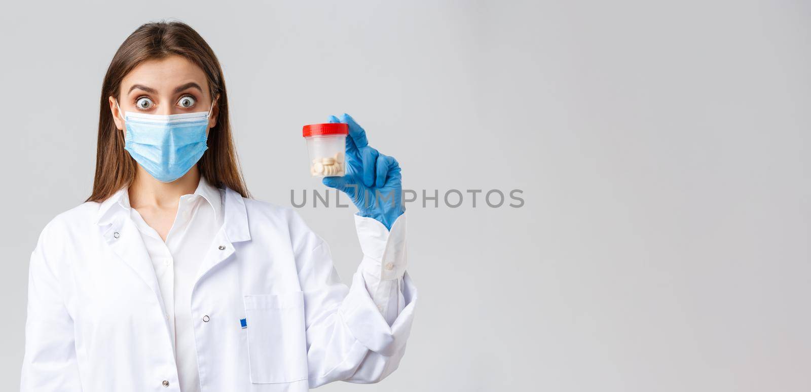 Covid-19, preventing virus, healthcare workers and quarantine concept. Surprised doctor in tech lab clinic impressed with new medicine, showing container with working pills or drugs.