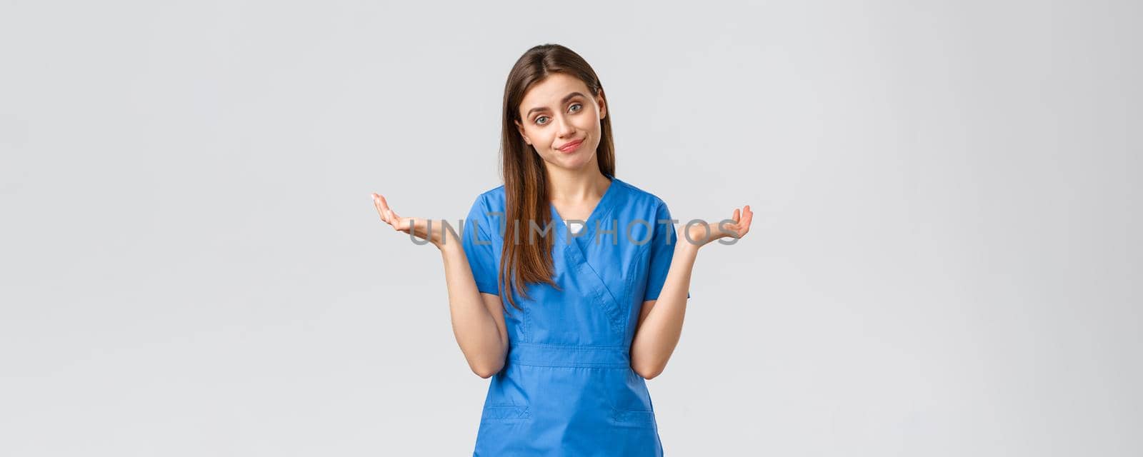 Healthcare workers, prevent virus, insurance and medicine concept. Doctor shrugging as cant tell, have no idea, sorry dont know. Female nurse in blue scrubs spread hands sideways by Benzoix