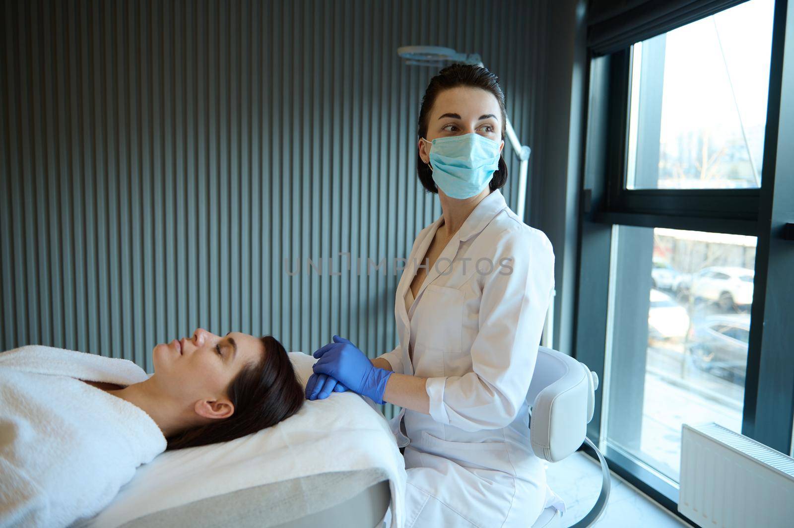 Professional masseuse, massage therapist and relaxed female patient- middle aged woman on a couch, enjoying beauty and wellness procedures in spa salon