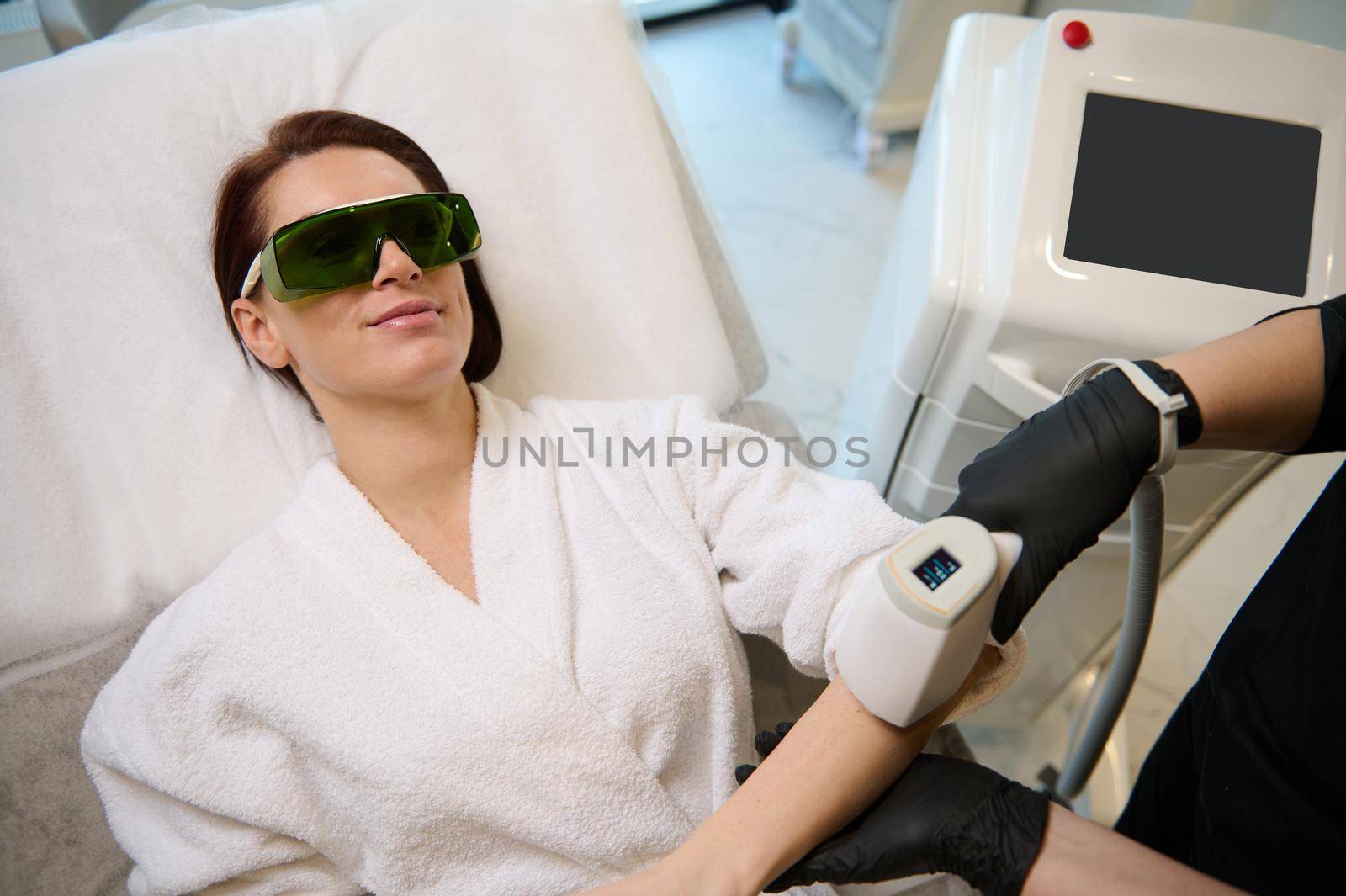 Overhead view of a middle aged beautiful Caucasian woman undergoing epilation procedure on hands in beauty salon. Body Care. Laser Hair Removal. Epilation Treatment. Smooth Skin.