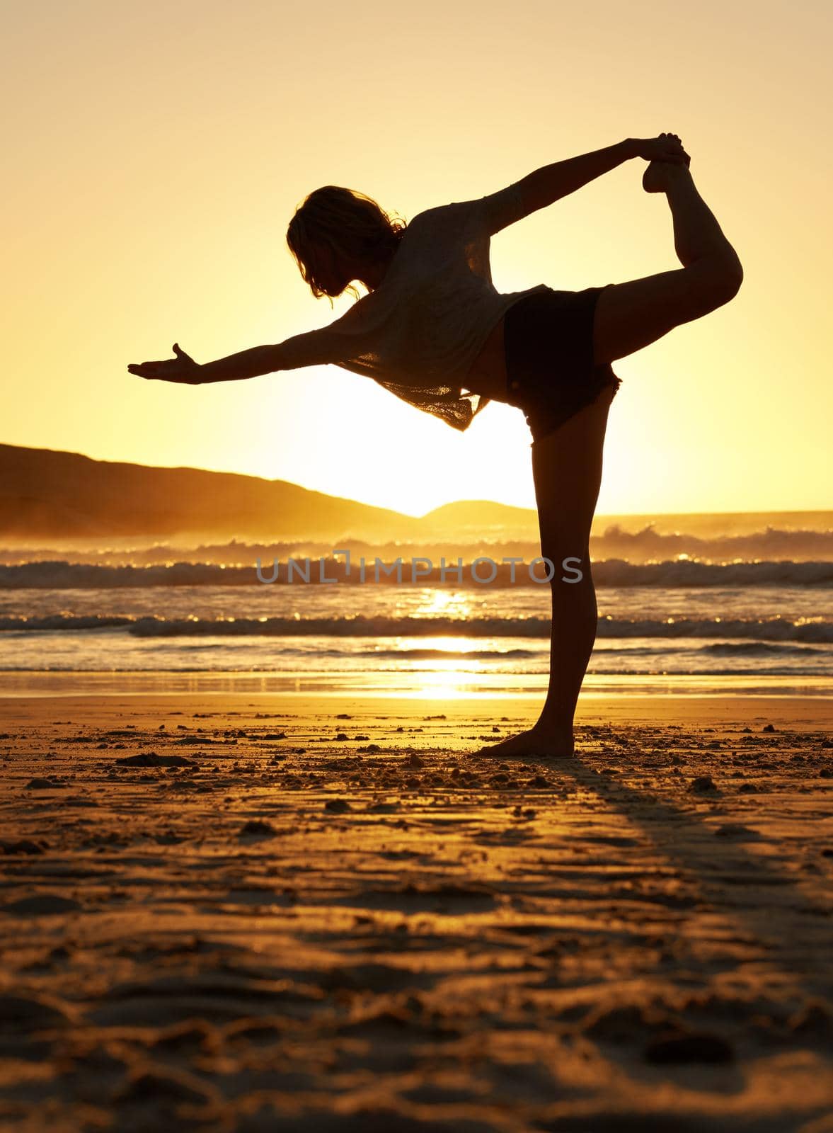 Shot of a young woman doing yoga on the beach.