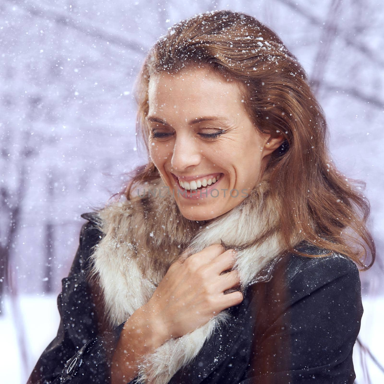 A moment of warmth. Shot of an attractive woman smiling in the snow. by YuriArcurs
