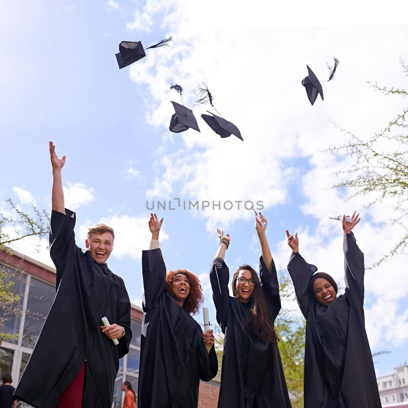 Woohoo Bring it on. Low angle shot of student throwing their graduation hats into the air. by YuriArcurs