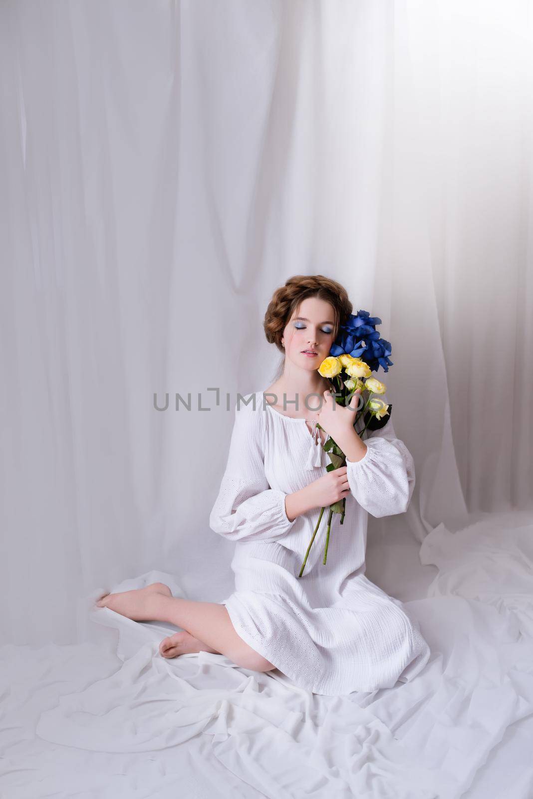 Caucasian Ukrainian teenager sitting in the studio in a dress and ellow-blue flowers on a white background during the war. Calm lady is sleeping. Concept - Stop the war in Ukraine.