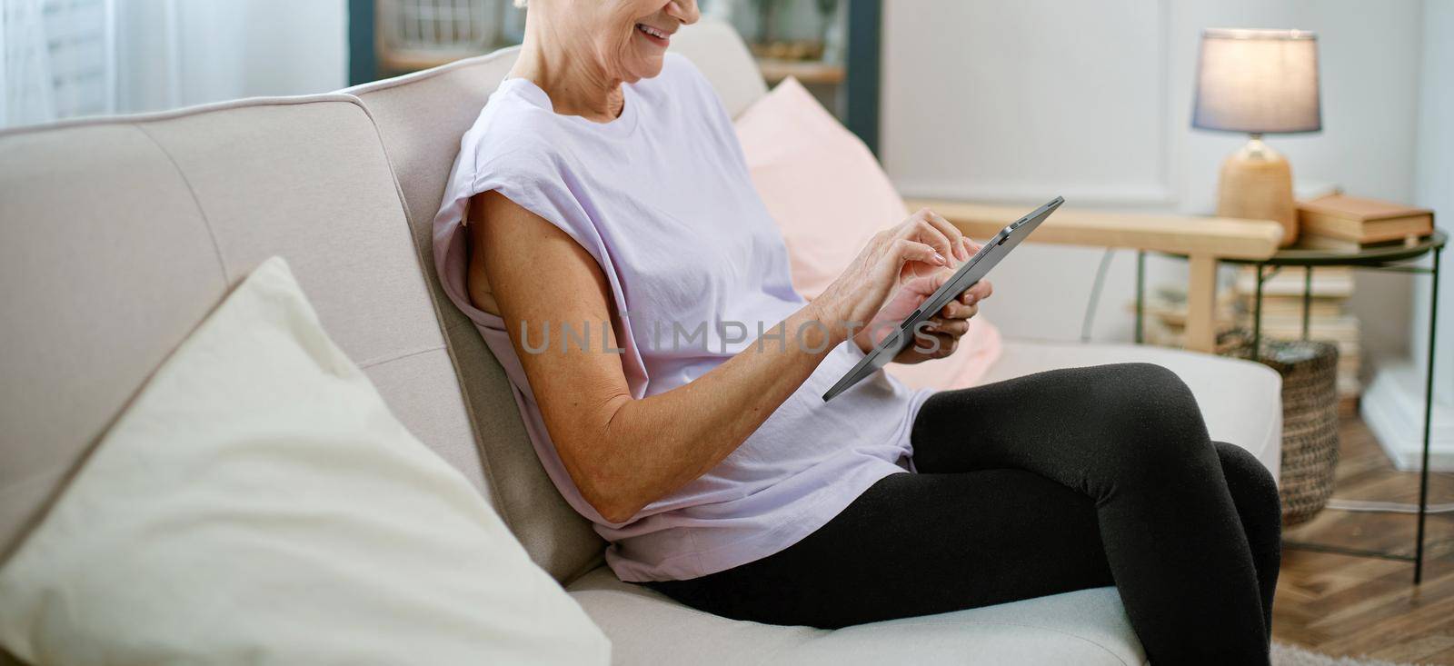 elderly woman looking at the screen of her digital tablet . by SmartPhotoLab