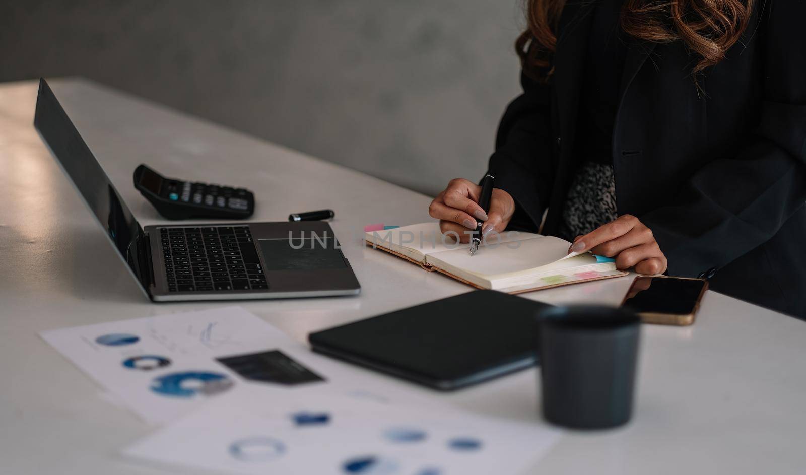 Close up businesswoman working with laptop and taking notes at office. business financial concept.