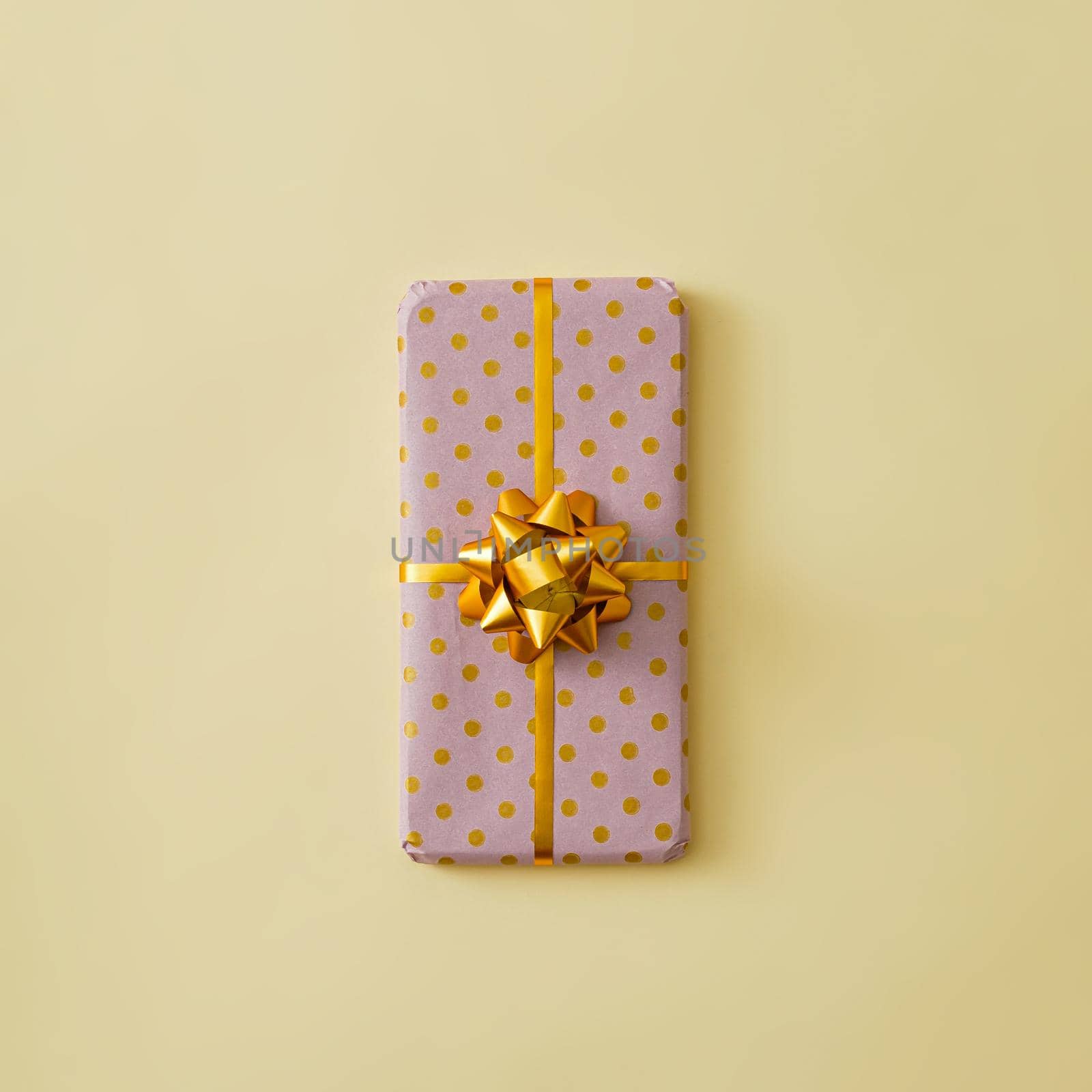 The mobile phone is gift-wrapped with a gold ribbon and a bow. Minimal modern gift concept. by sergii_gnatiuk
