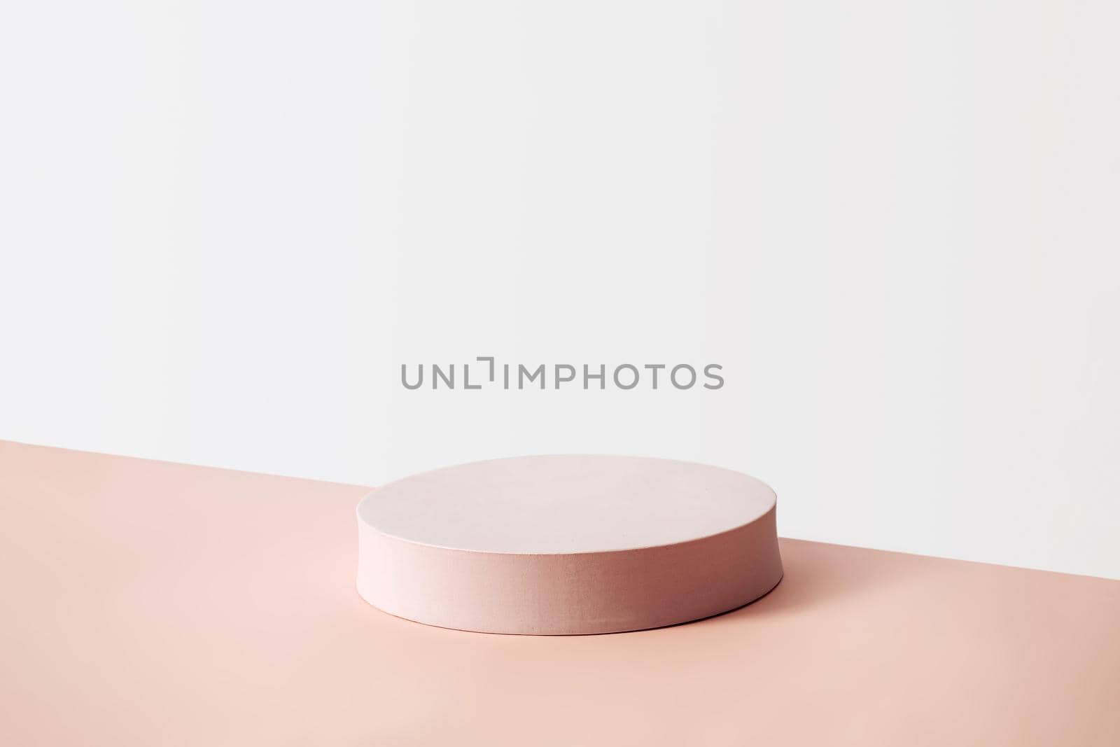 Product placement and advertising concept with empty display with a circular beige pedestal against an off white wall