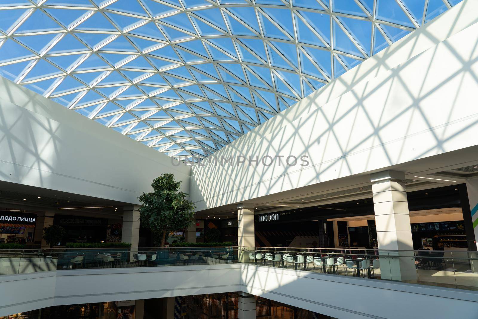 Grodno, Belarus - April 07, 2021: The interior of the modern large shopping and entertainment complex Trinity with a transparent glass roof.