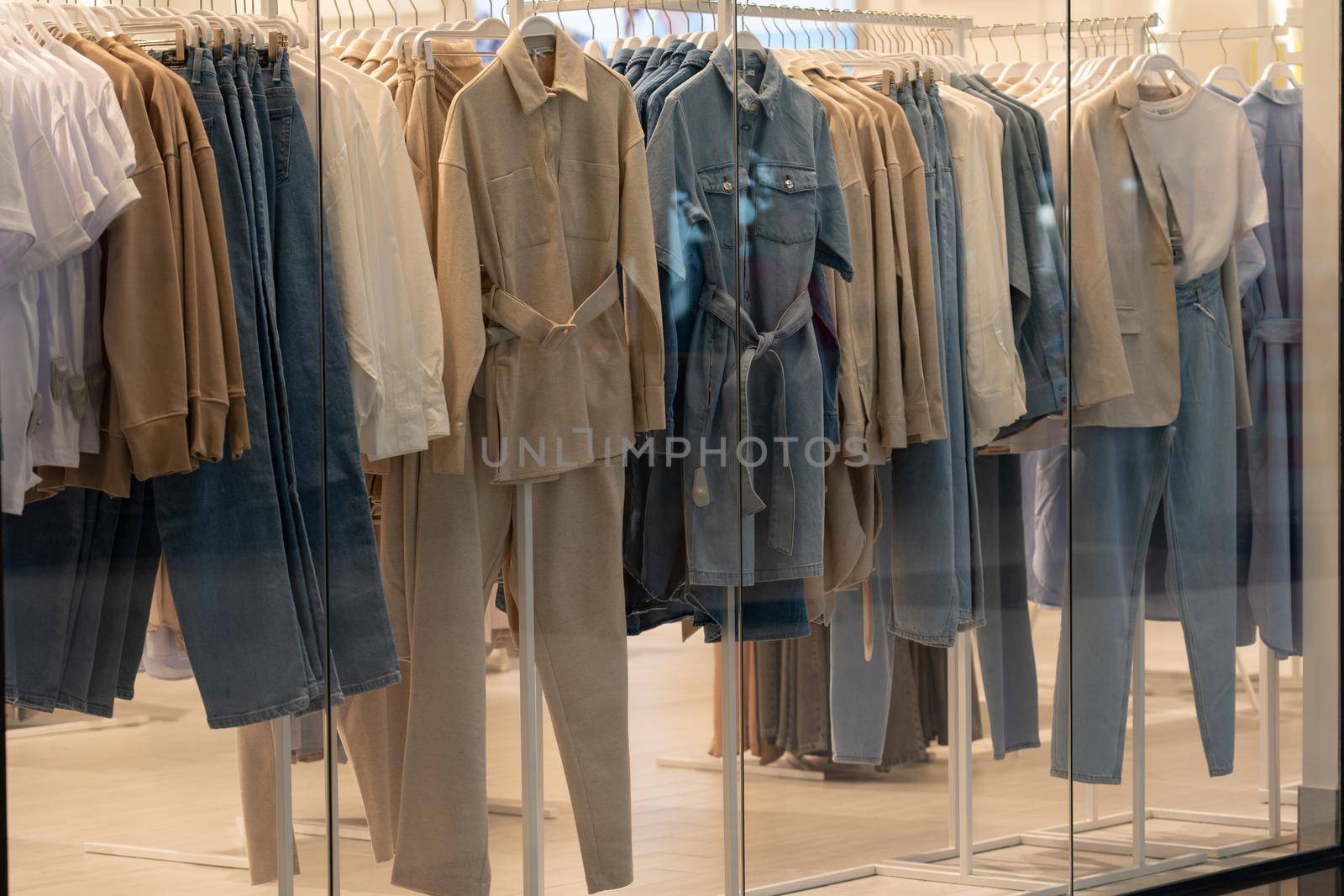 Showcase with female clothes in clothing store, nobody. Coats, jackets and shoes in fashion boutique