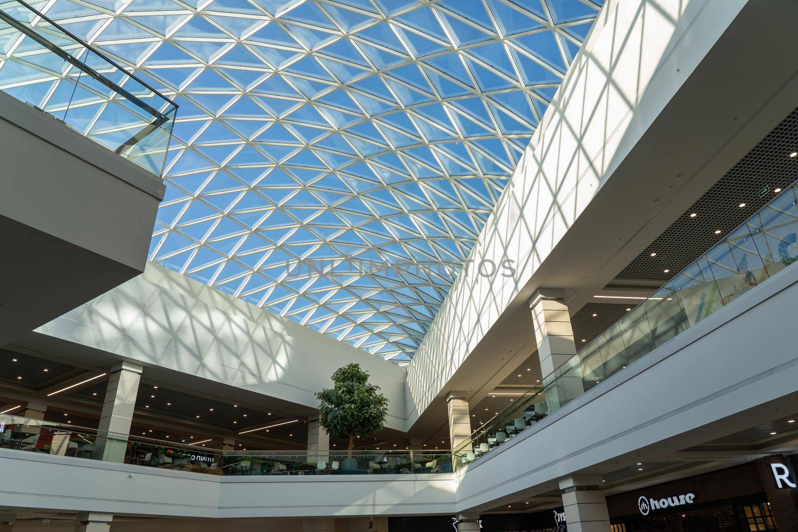 Grodno, Belarus - April 07, 2021: The interior of the modern large shopping and entertainment complex Trinity with a transparent glass roof.