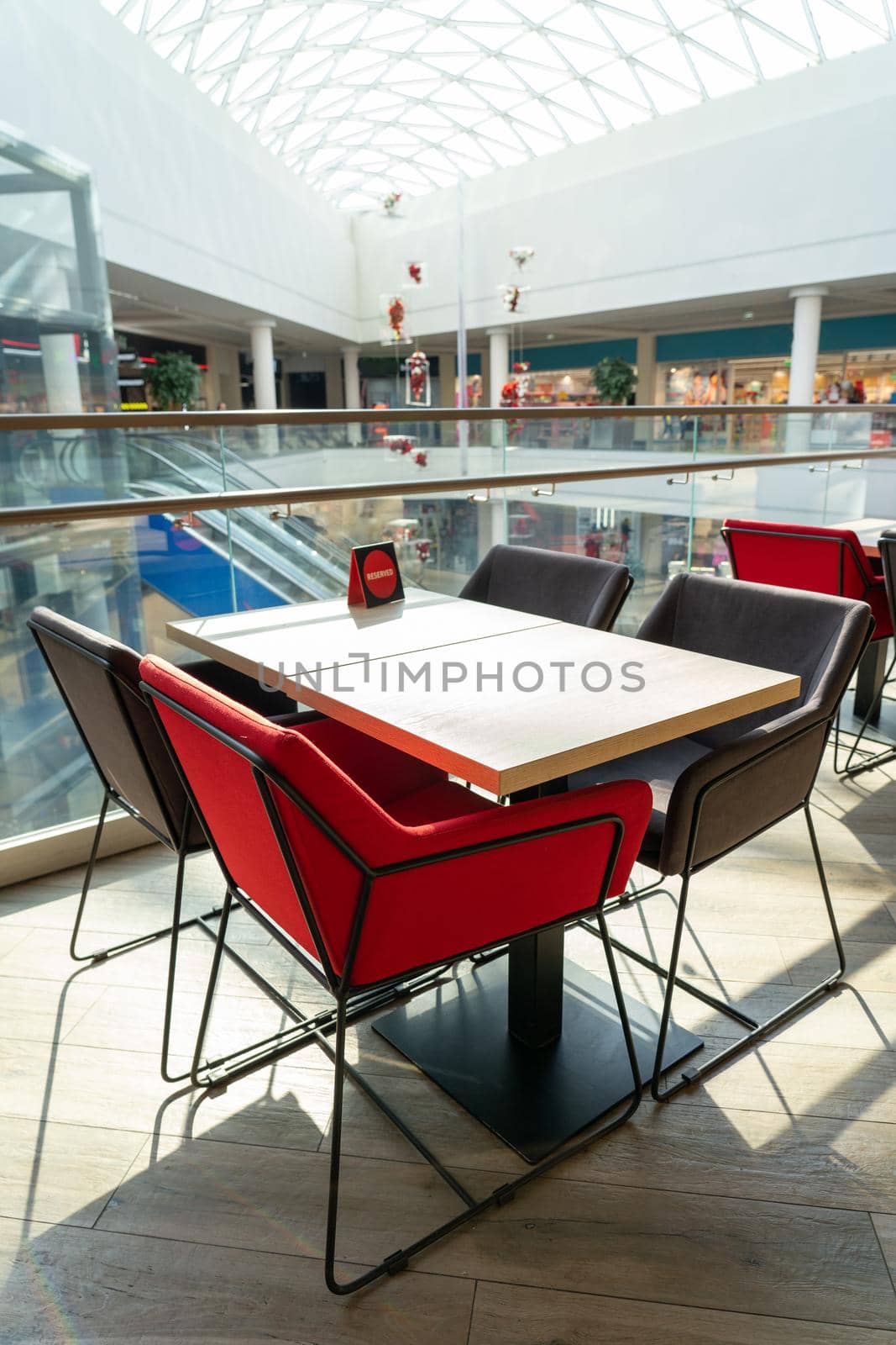 A table and soft chairs for visitors to the food court of a modern shopping center. The table is reserved.
