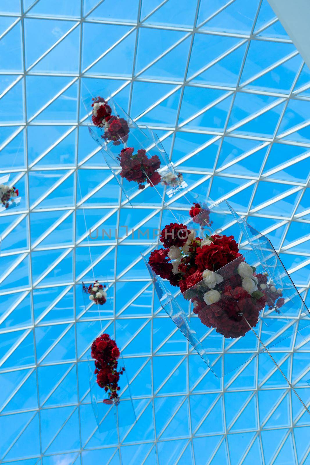 Transparent glass roof of a modern shopping center. Flower decorations are suspended under the roof of the building.