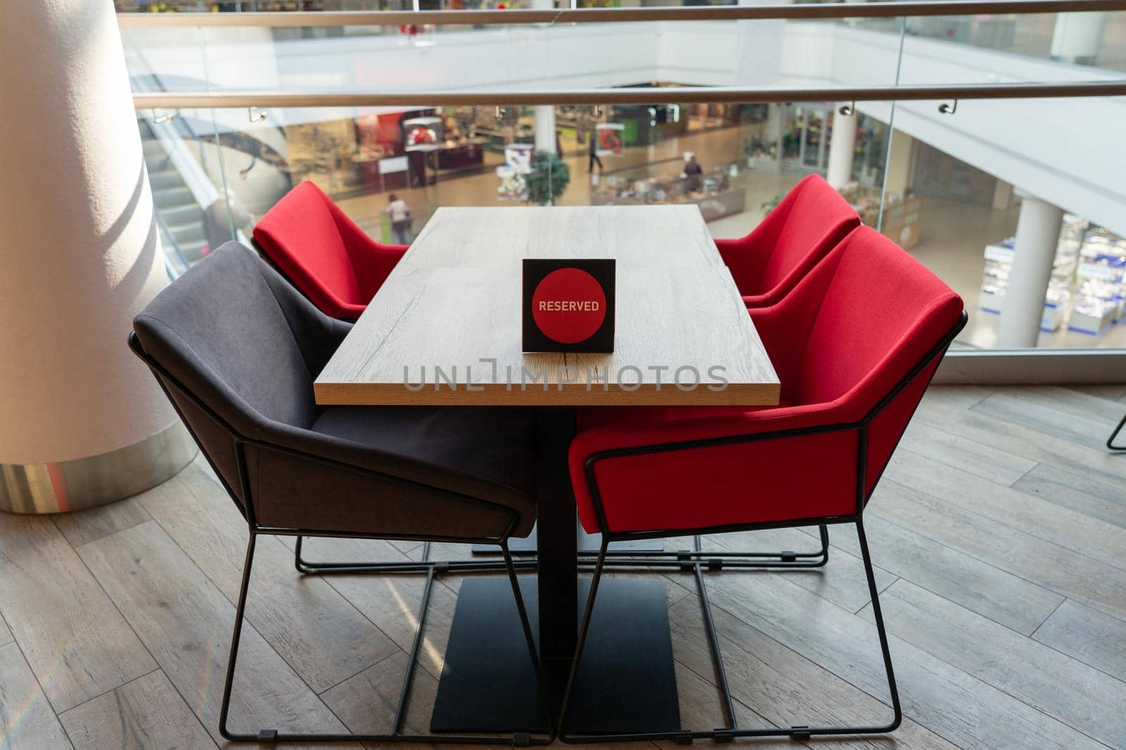 A table and soft chairs for visitors to the food court of a modern shopping center. The table is reserved.