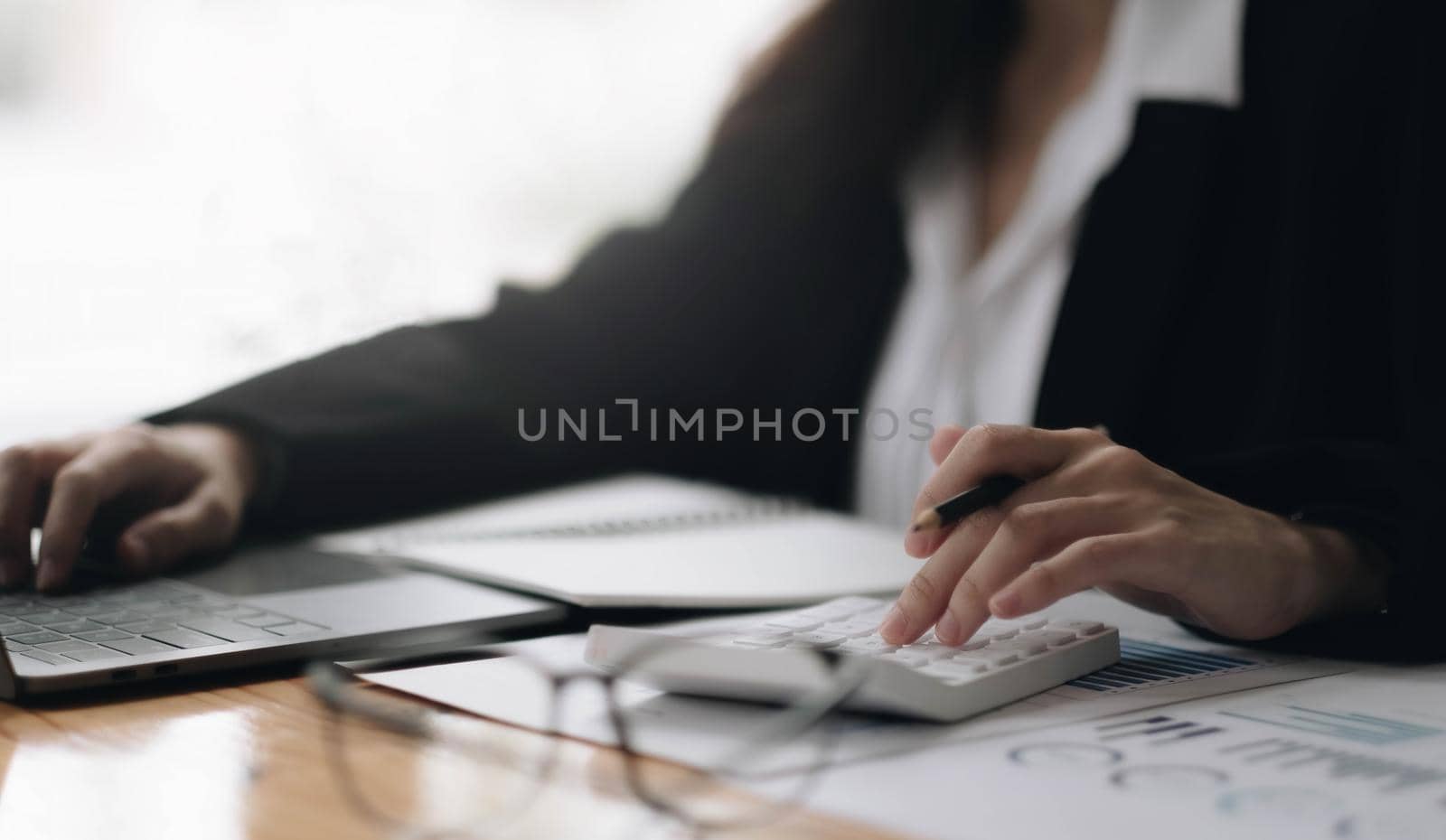 Consult financial concept. Businesswoman pointing at calculator and using laptop computer. by wichayada