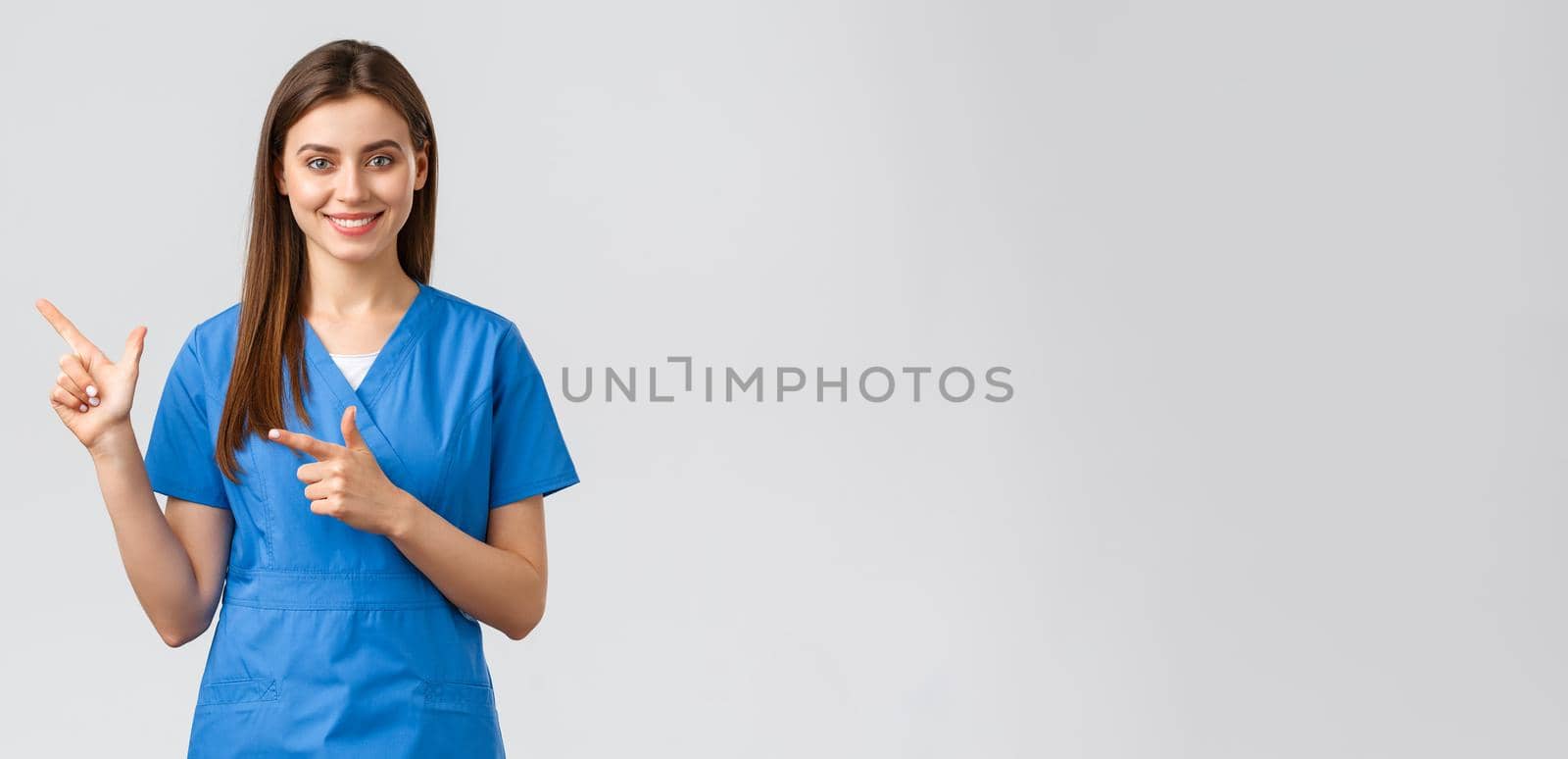 Healthcare workers, prevent virus, insurance and medicine concept. Professional smiling, attractive female nurse or doctor in blue scrubs, physician pointing finger left at banner, recommend clinic.