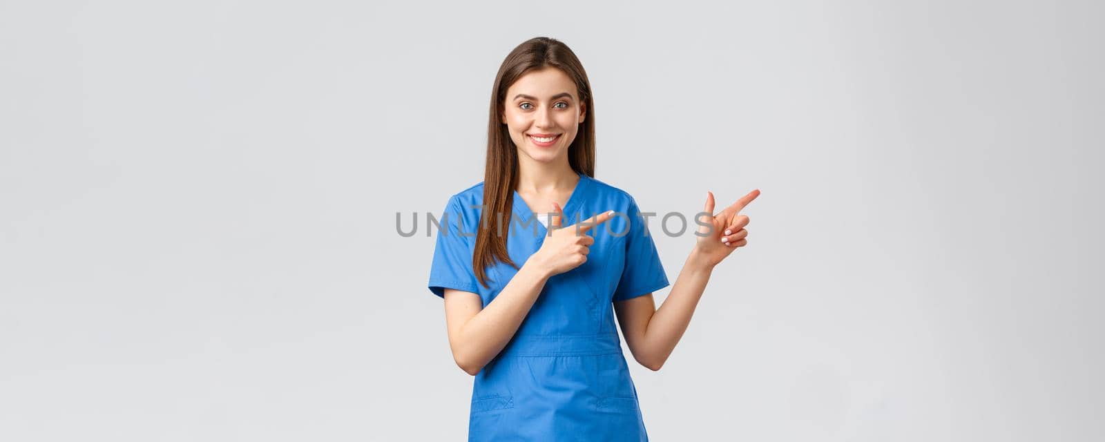 Healthcare workers, prevent virus, insurance and medicine concept. Smiling nurse or female doctor in blue scrubs, pointing fingers down, inform about coronavirus news, show information by Benzoix