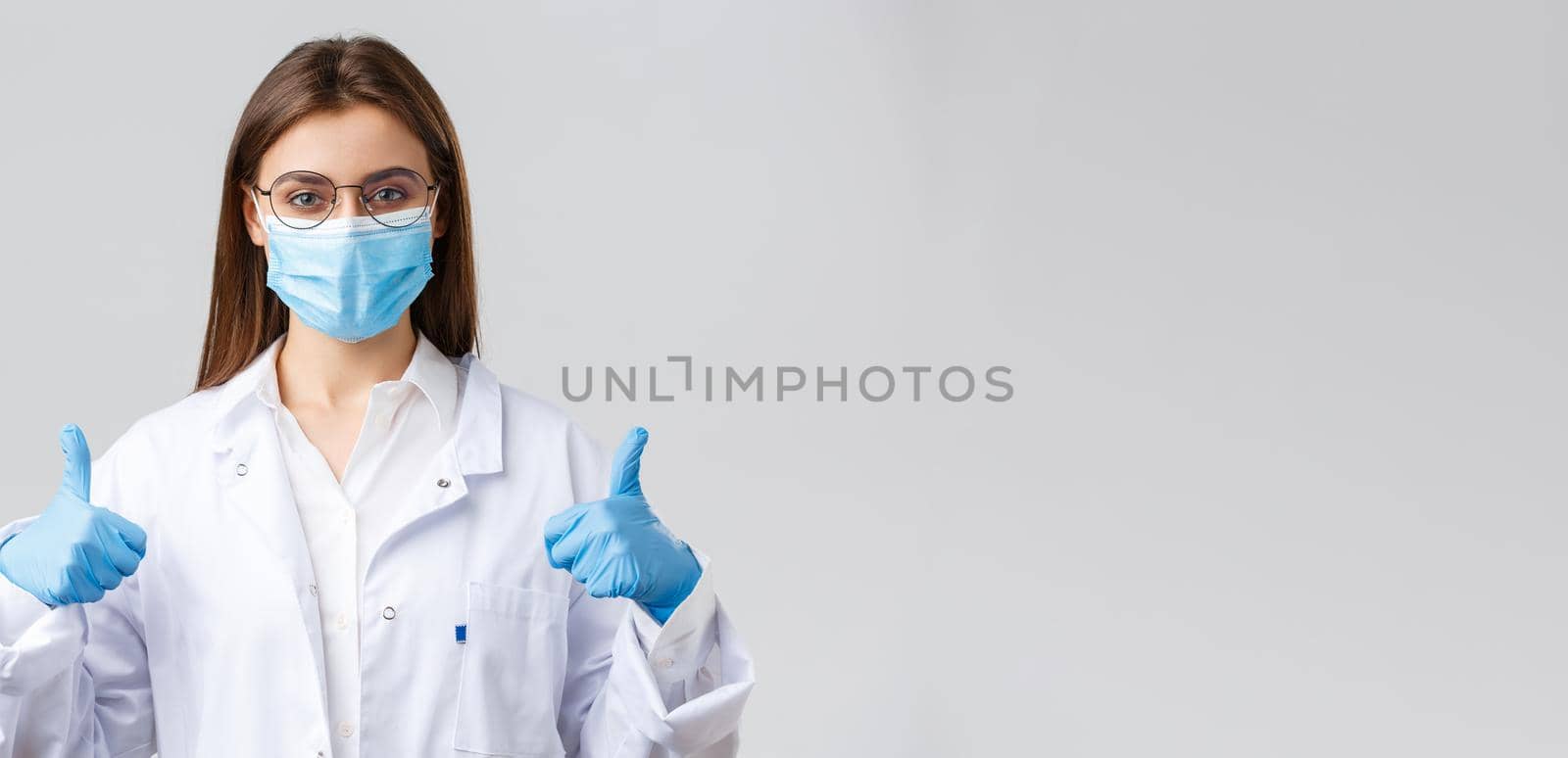 Covid-19, preventing virus, healthcare workers and quarantine concept. Cheerful female doctor, physician in white scrubs and rubber gloves, show thumb-up, ask use protection against corona infection.