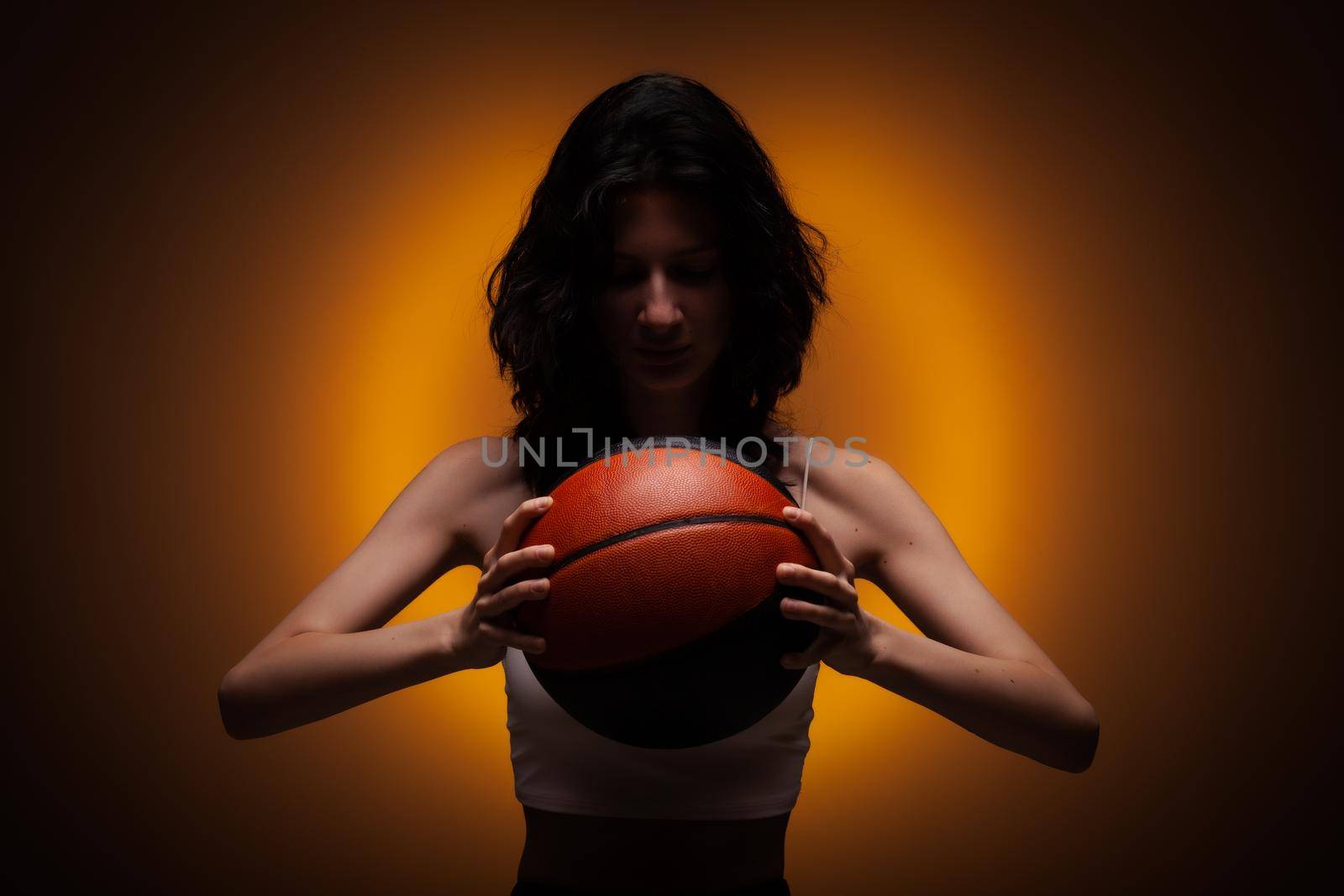 Teenage girl with basketball. Studio portrait on orange colored background.. by kokimk