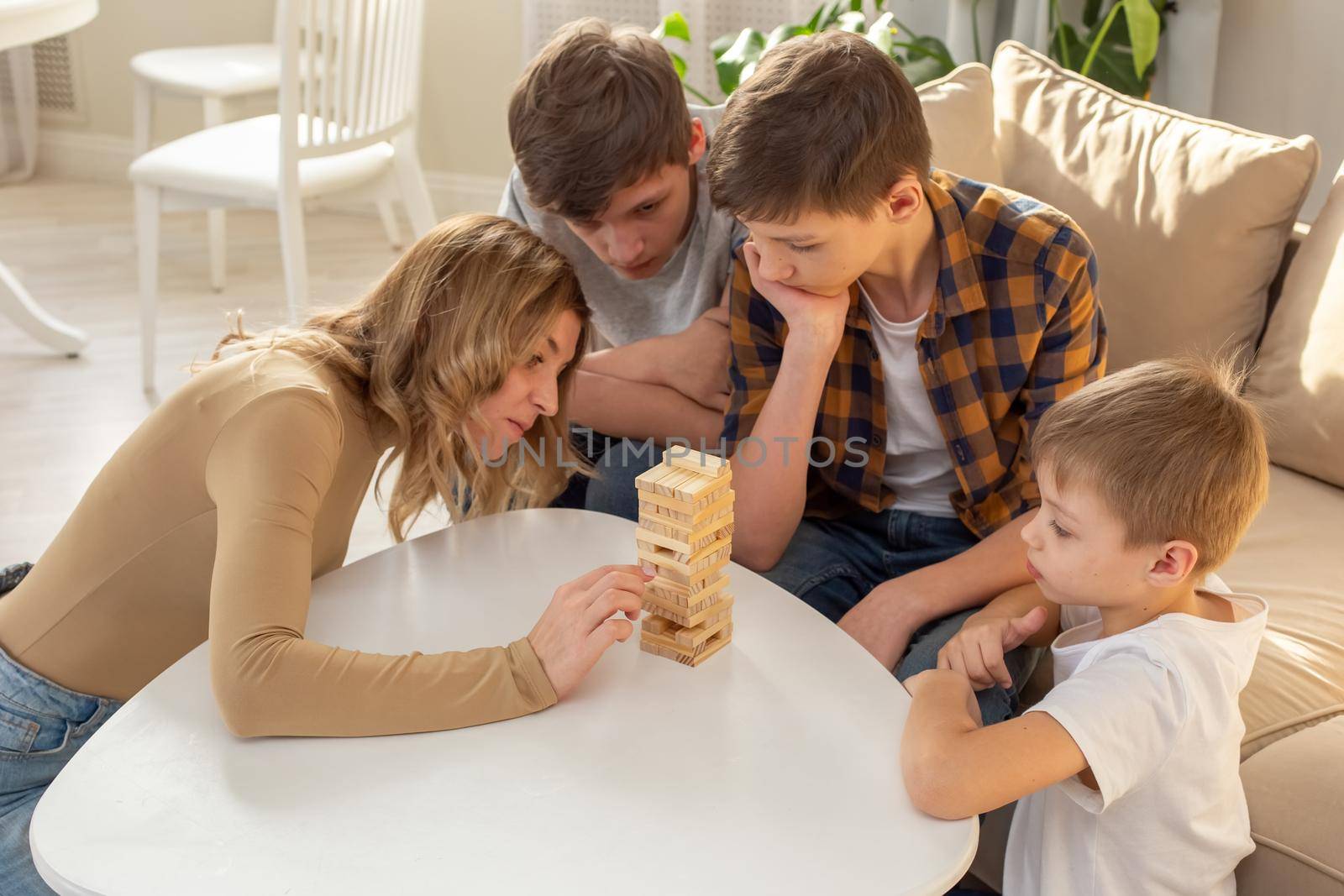 Family , in room play a board game made of wooden rectangular blocks by Zakharova