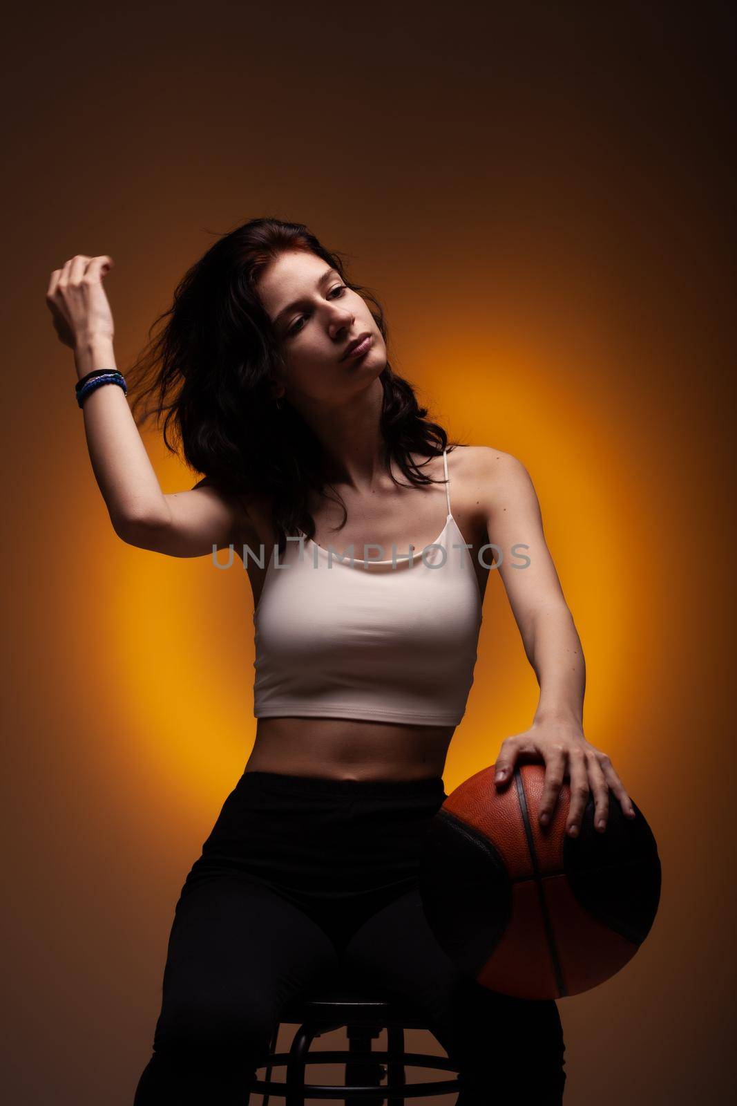 Teenage girl with basketball. Studio portrait on orange colored background.. by kokimk