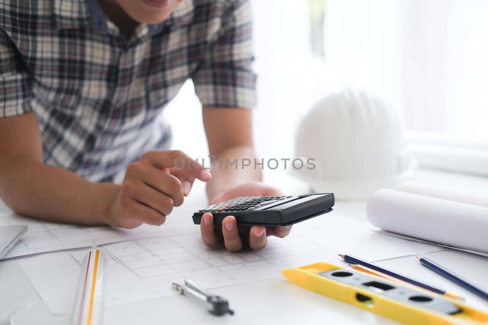 Young man was designing a building or architecture with a ruler, pen, pencil, tape measure, architect hat and other equipment.