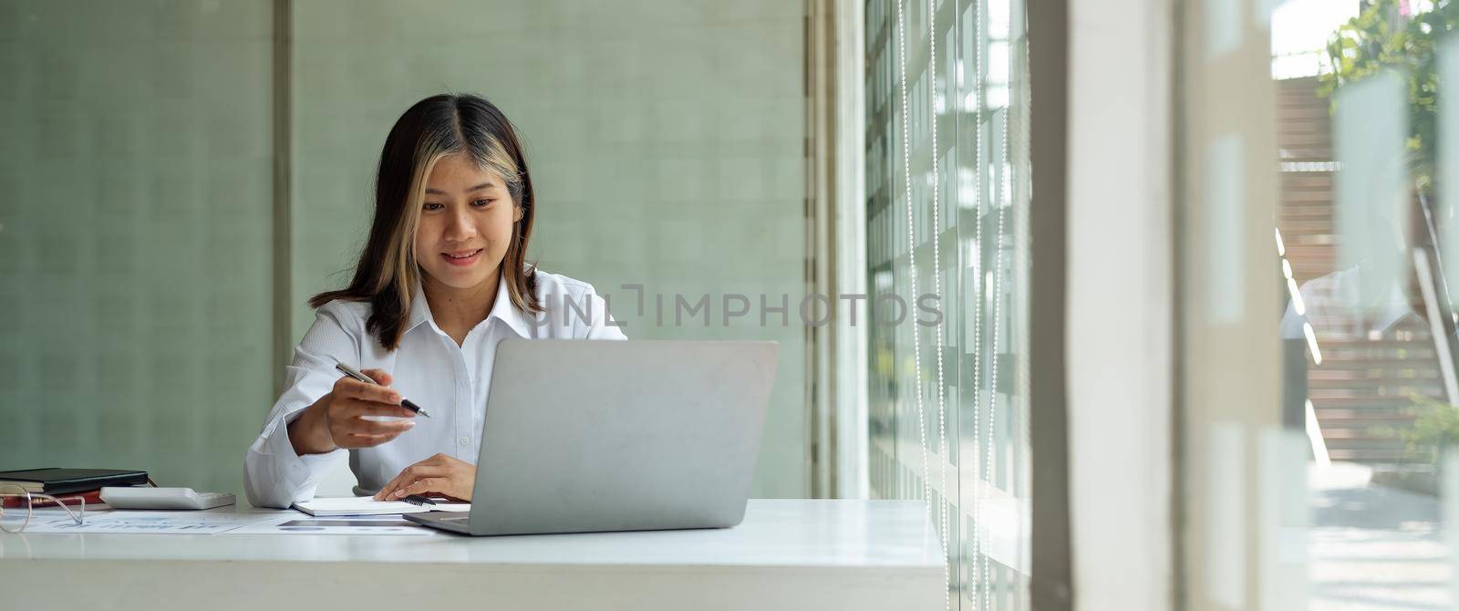 Crop shot of charming asian businesswoman working with laptop accounting financial in office by nateemee