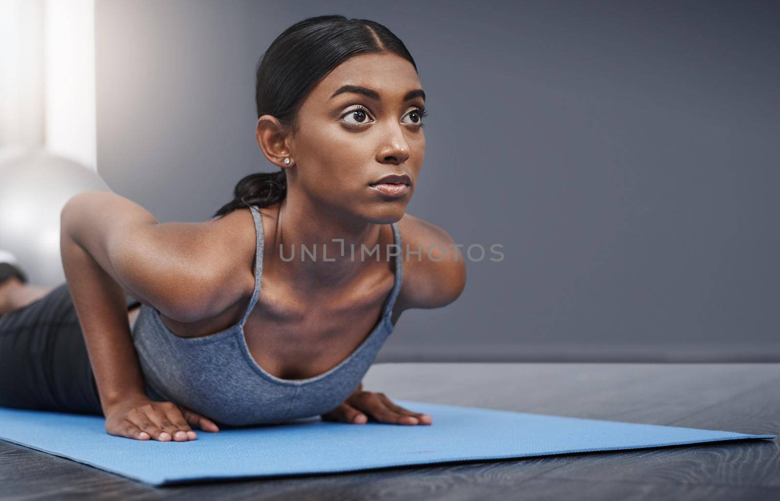 Shot of an attractive young woman busy exercising on her gym mat at home.